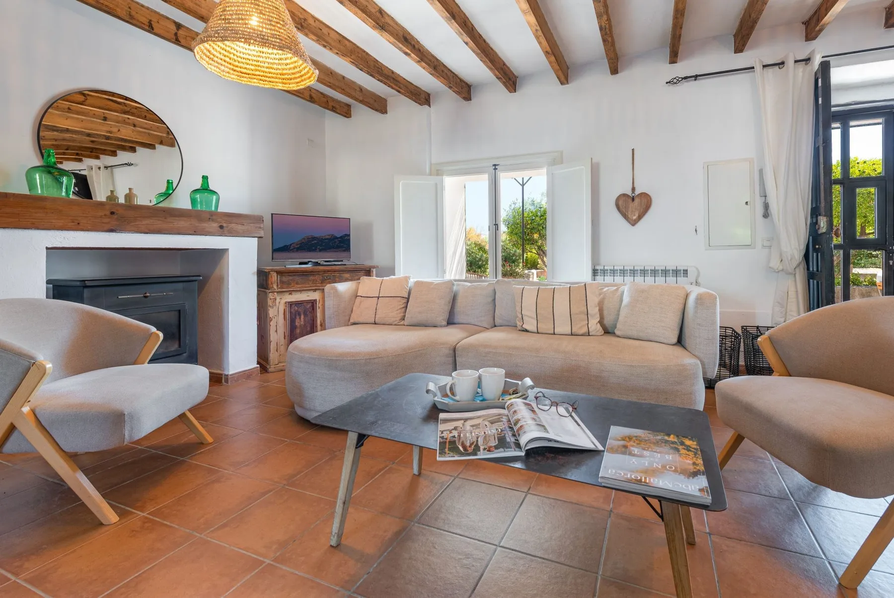 Una luminosa sala de estar cuenta con asientos cómodos, una chimenea y vigas vistas en el techo.