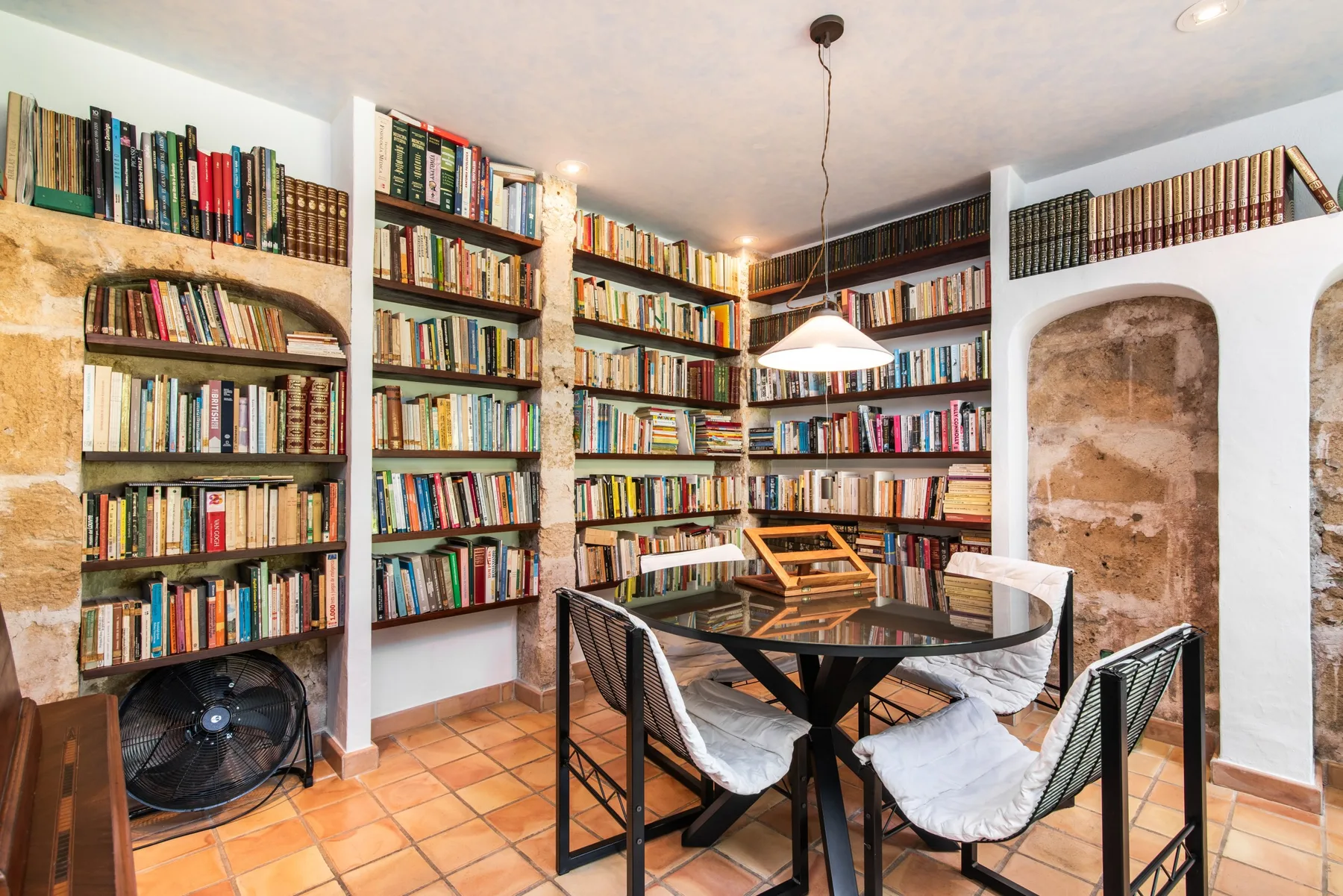 A library with bookshelves around a glass table and seating.