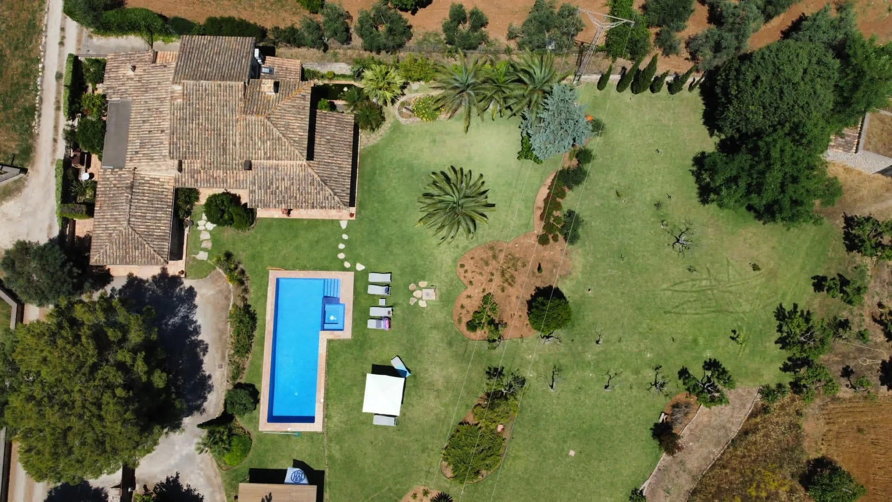 An aerial view of a house, swimming pool, and landscaped garden.