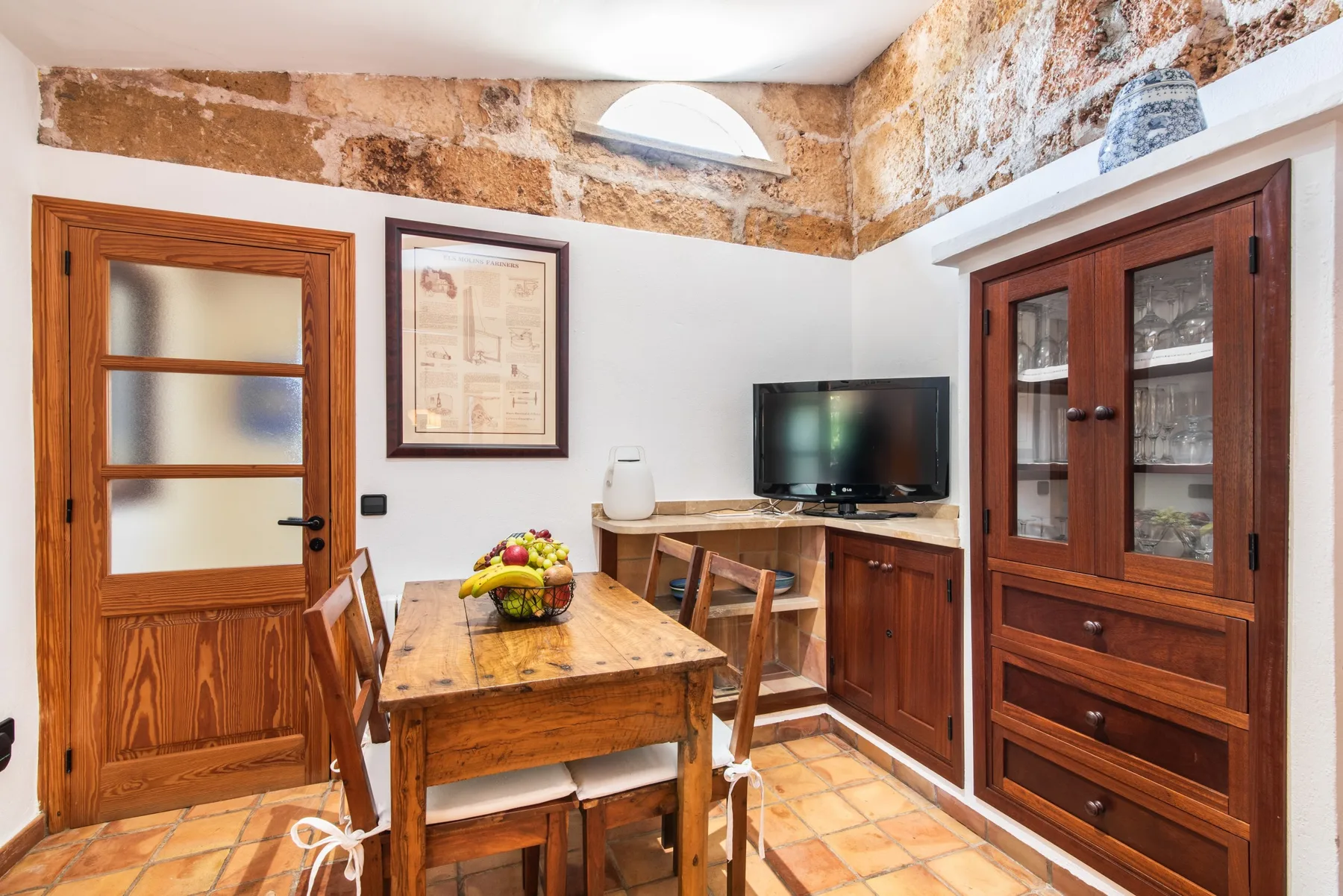 A dining area with a wooden table and a television on the counter.