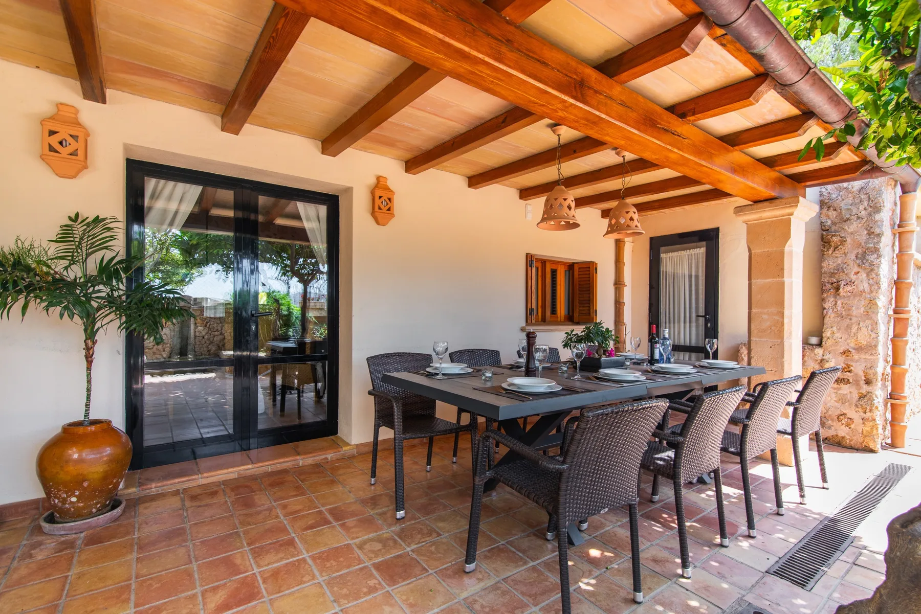 A covered patio dining area with a long table and woven seating.