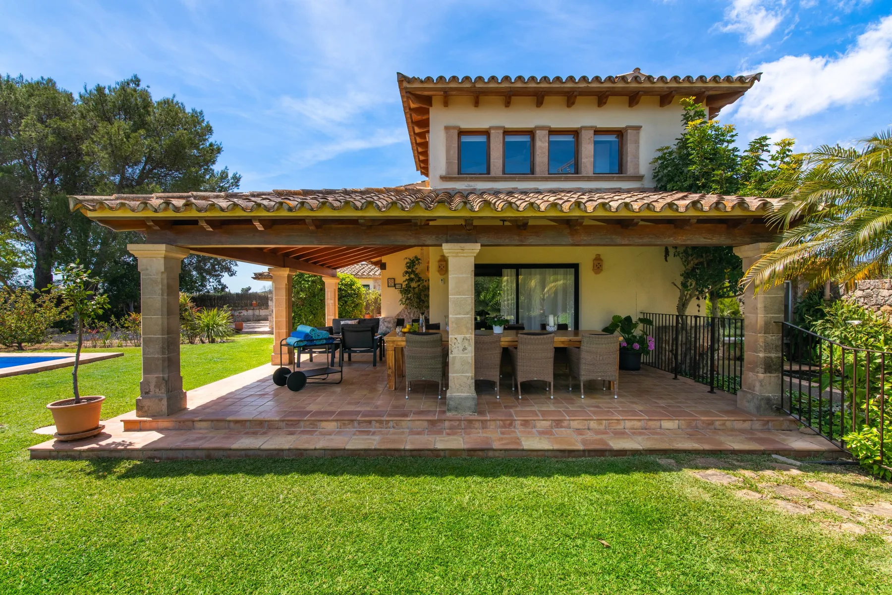 A house with a covered outdoor dining area opening onto a green lawn.