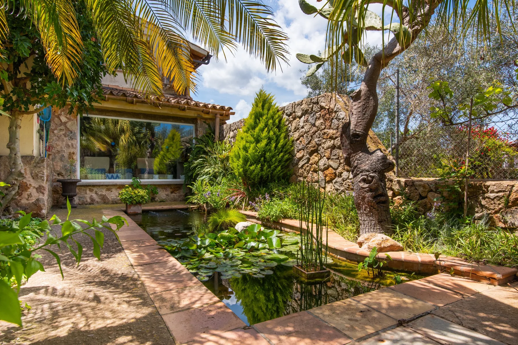 A landscaped garden with a pond and a stone path beside a house.