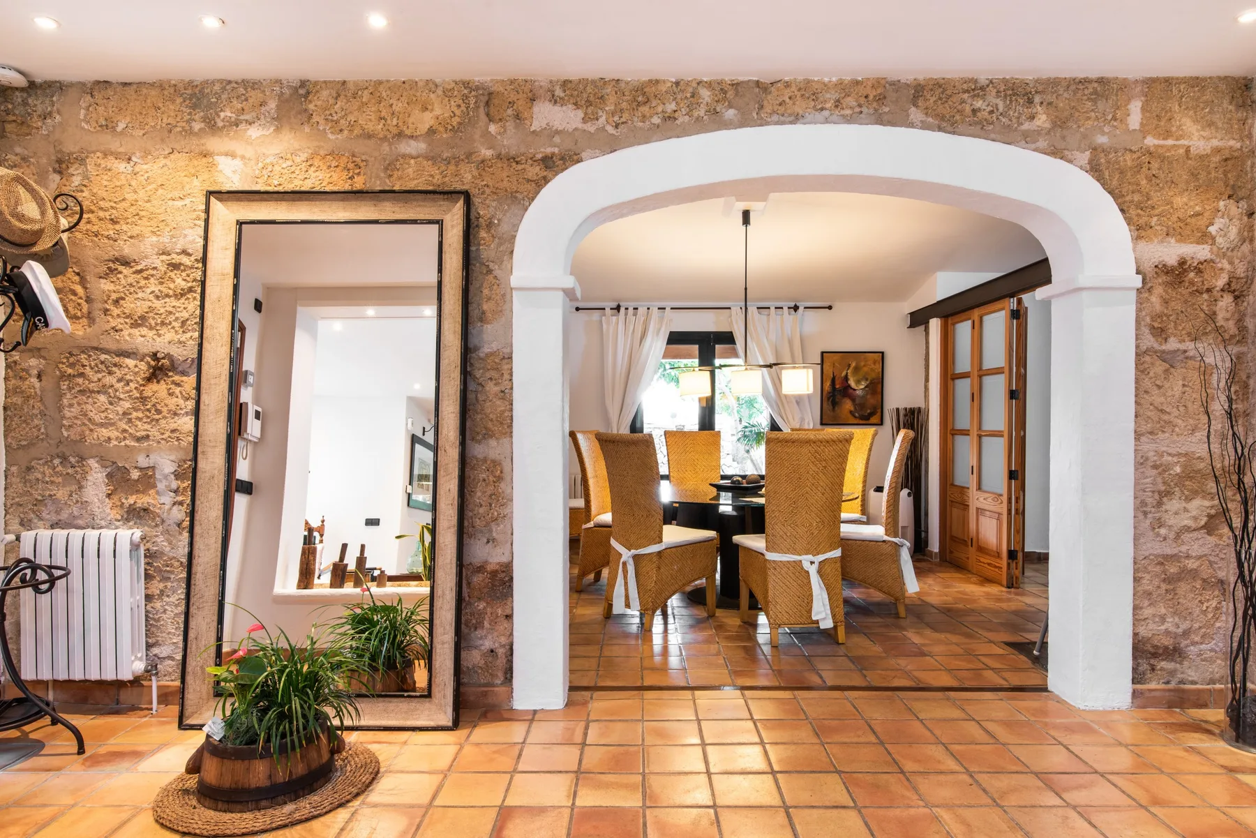 A rustic dining area is visible through a wide arch, with a table and seating.
