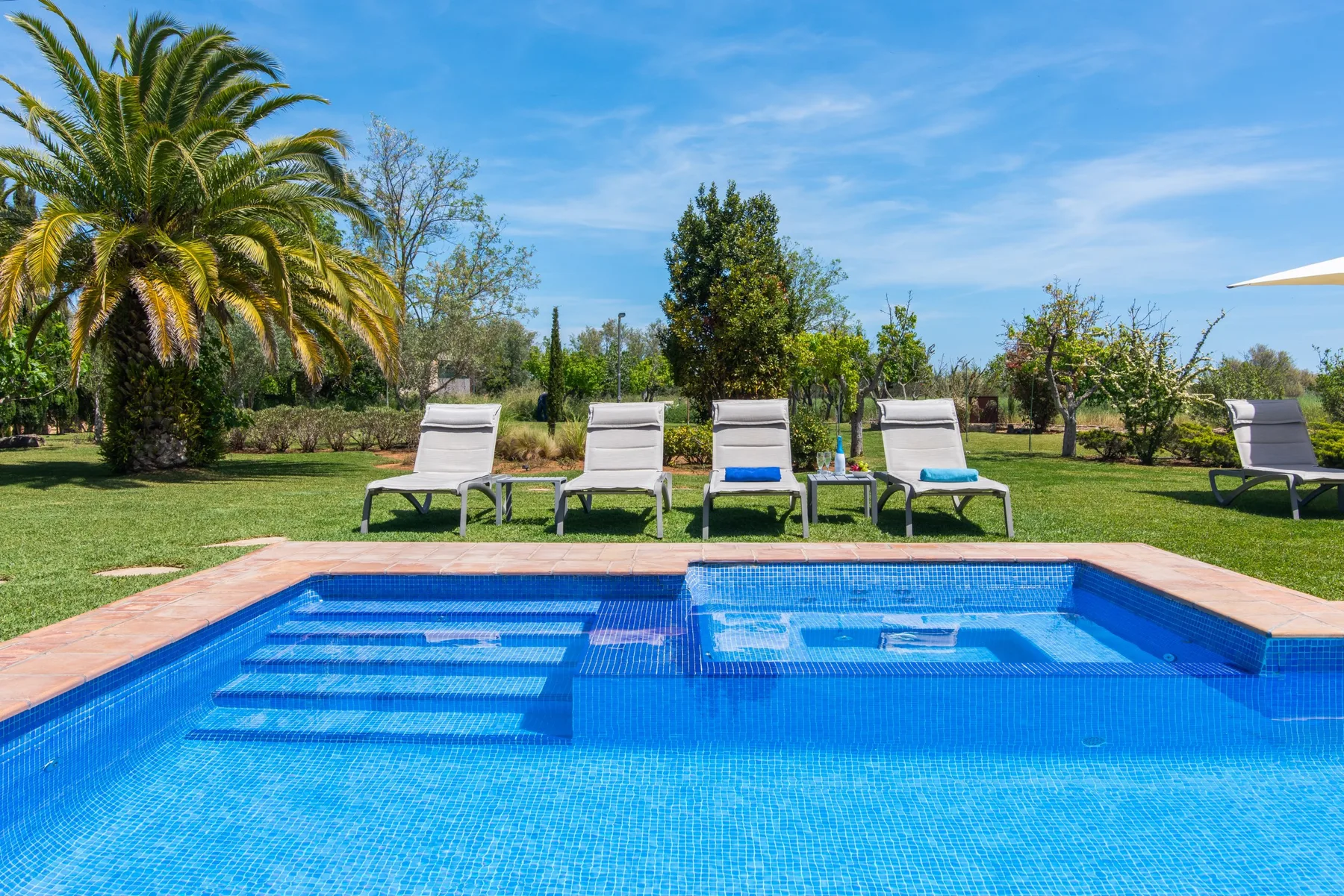 An outdoor swimming pool with lounge chairs on a green lawn.