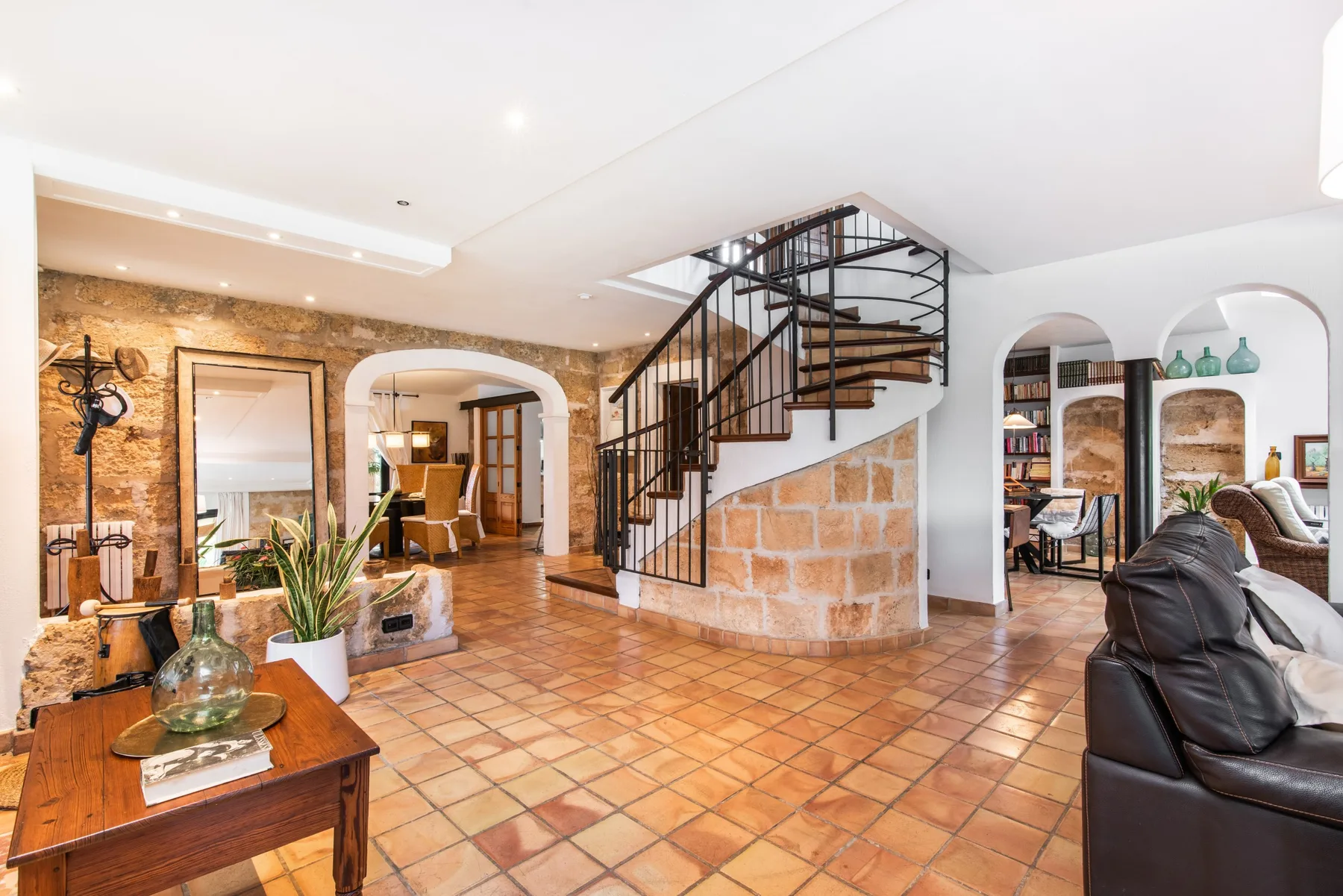 A warm-toned living area with tiled flooring and a curved staircase.