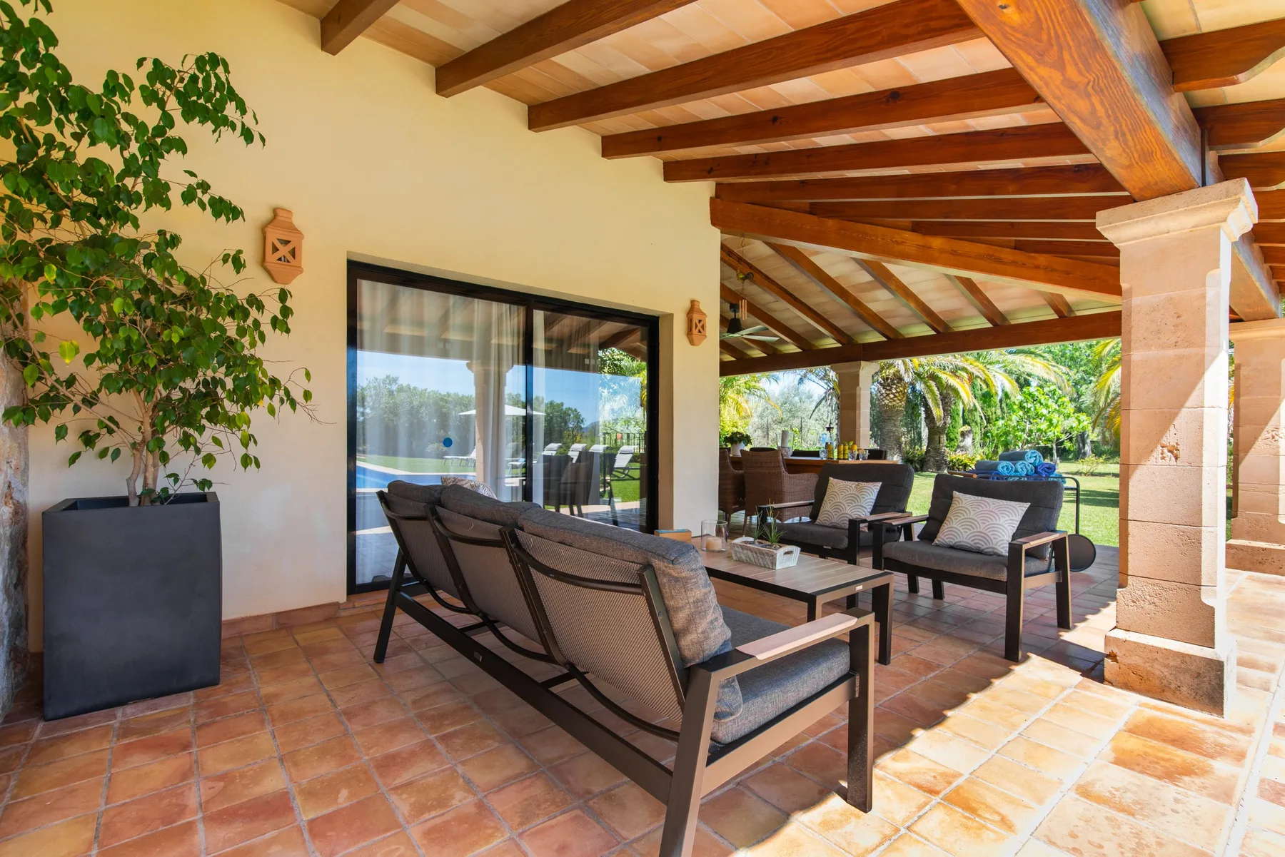 A covered patio with outdoor seating and a wooden-beam ceiling.