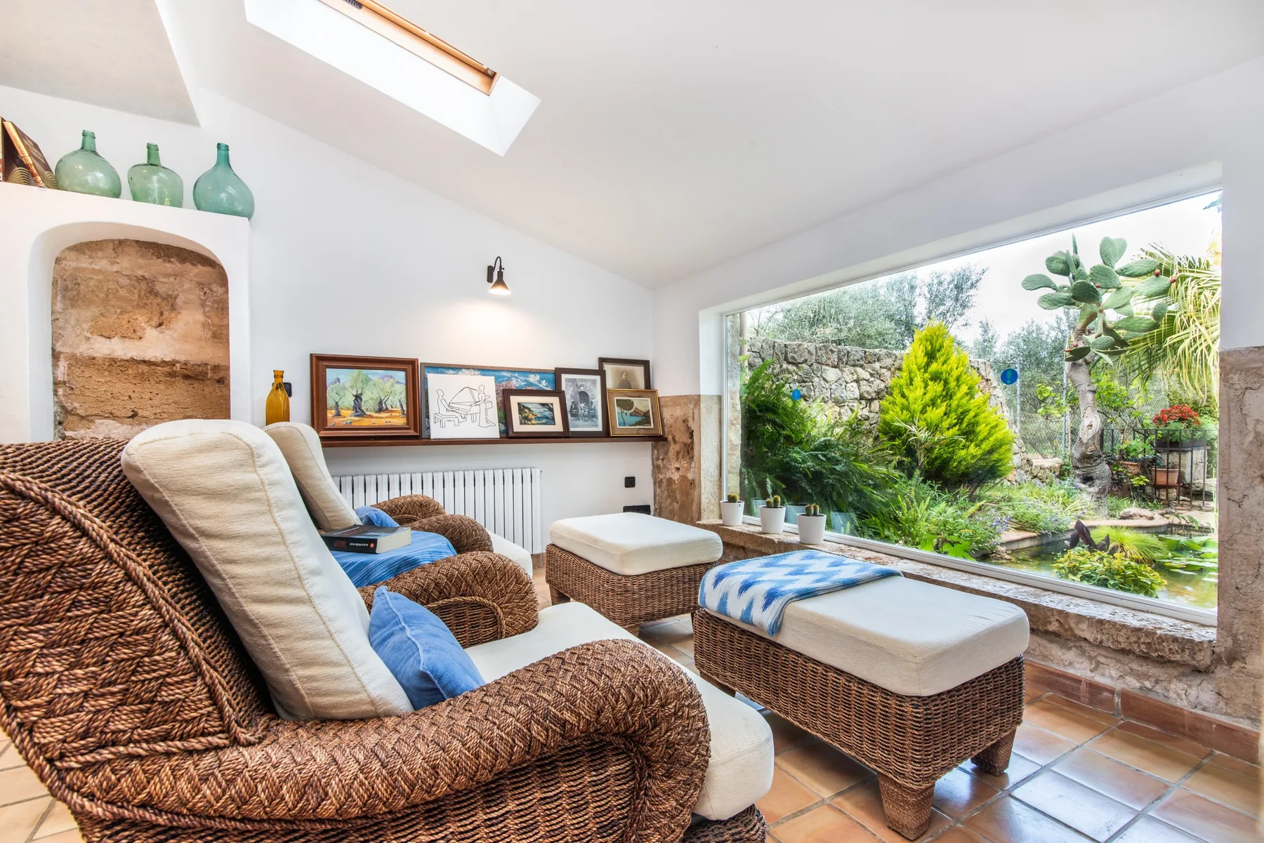 A sunroom seating area opens onto a lush garden through a wide glass window.