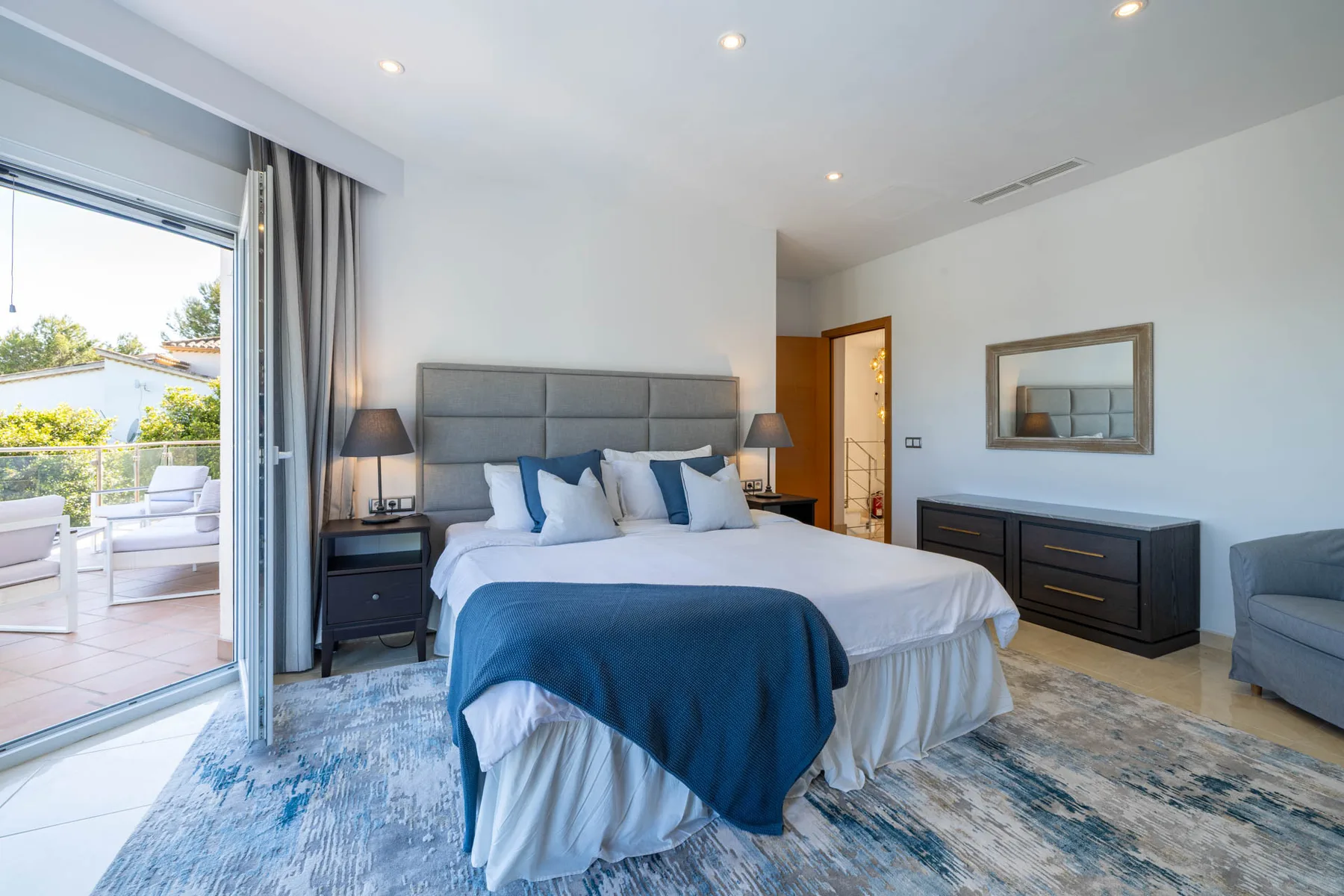 A bedroom with a neatly made bed and sliding glass doors opening to a patio.