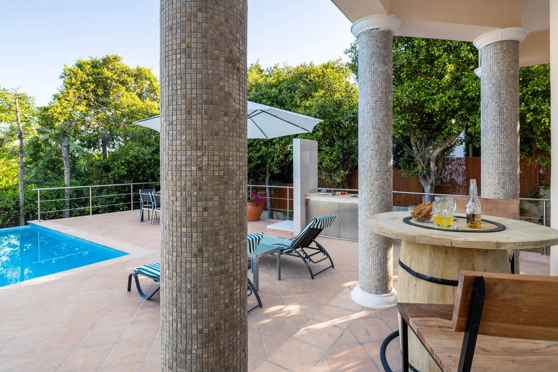 A poolside patio with lounge seating and a round outdoor table.