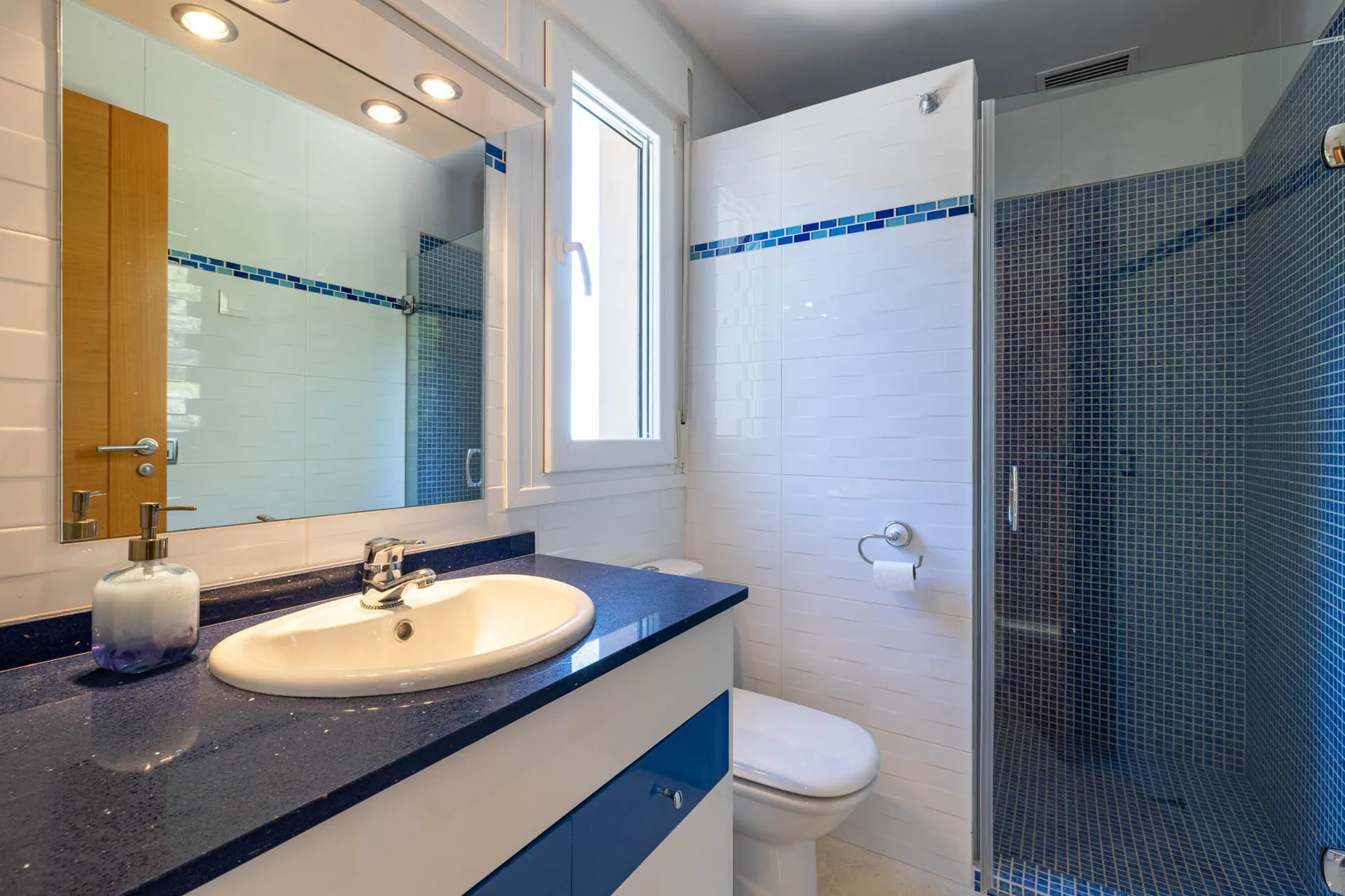 A bathroom with a sink, toilet, and tiled shower.