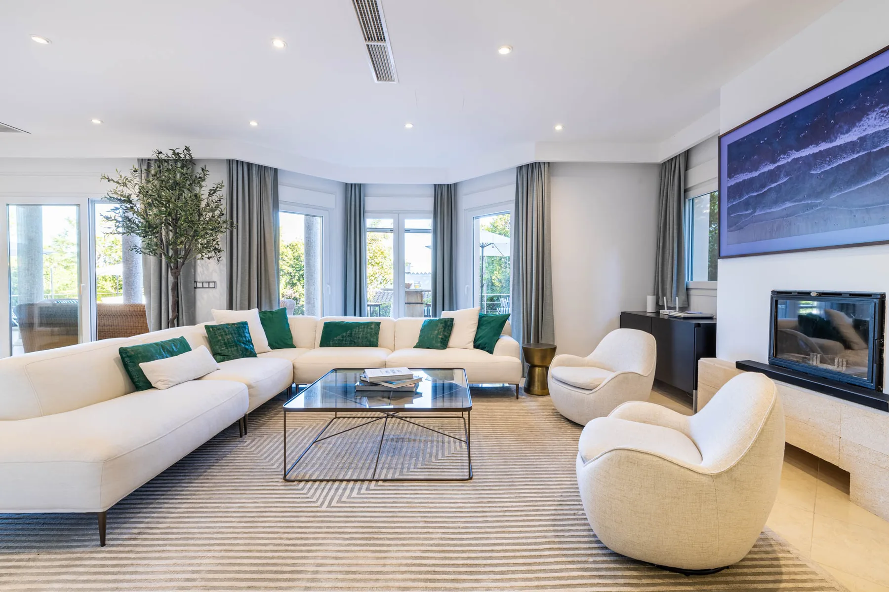 A bright living room with curved seating and a glass coffee table.