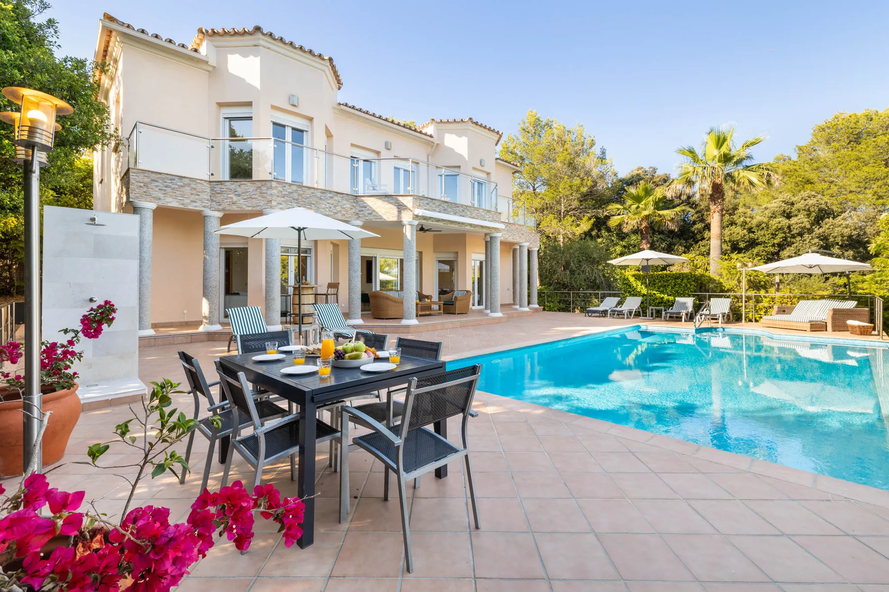 A swimming pool and outdoor dining area sit beside a white multi-story building.