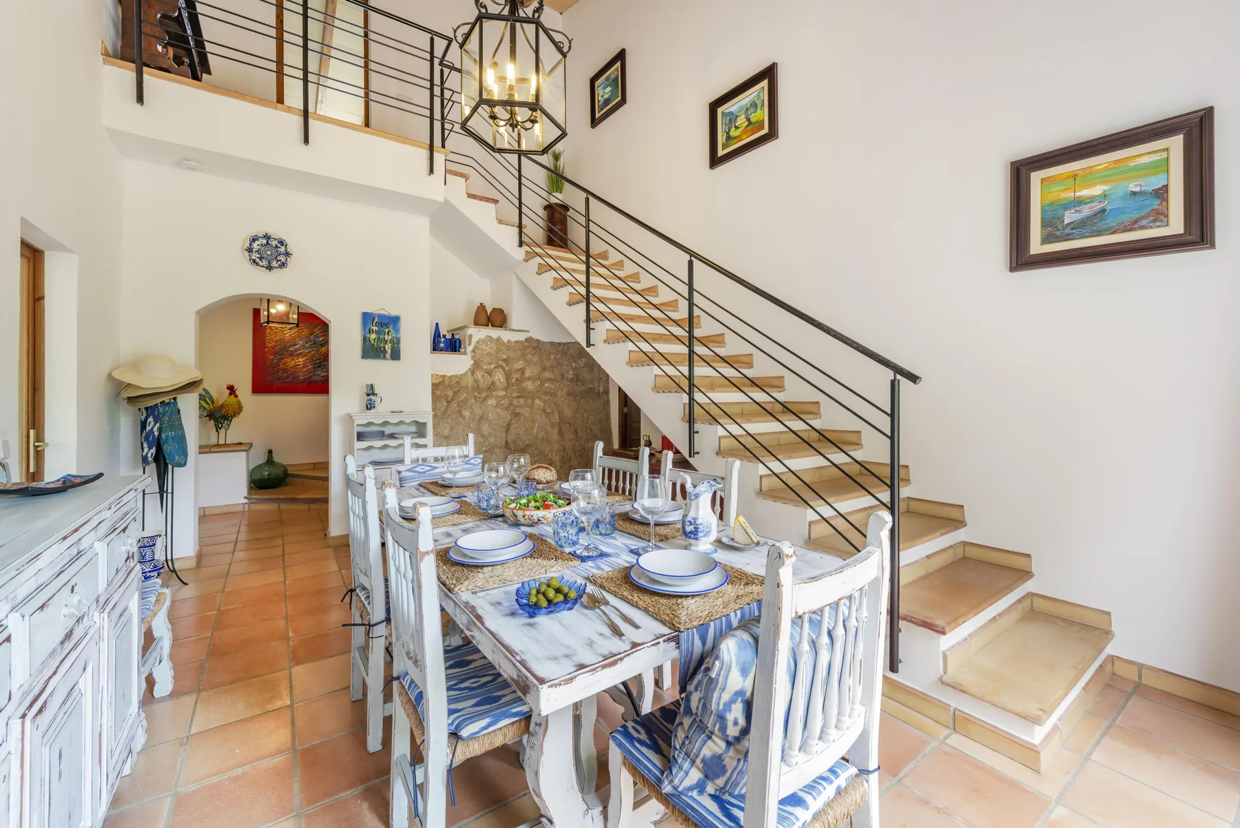 Comedor con una mesa larga preparada bajo una escalera.