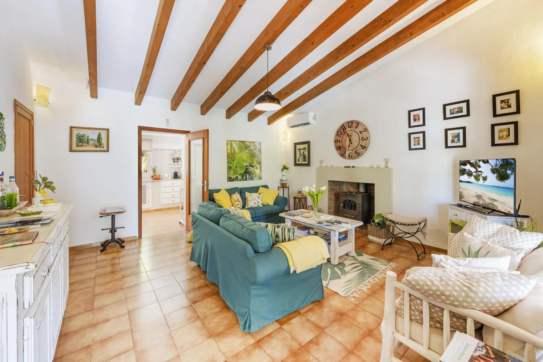 Una sala luminosa con asientos verde azulado, una chimenea y vigas a la vista.
