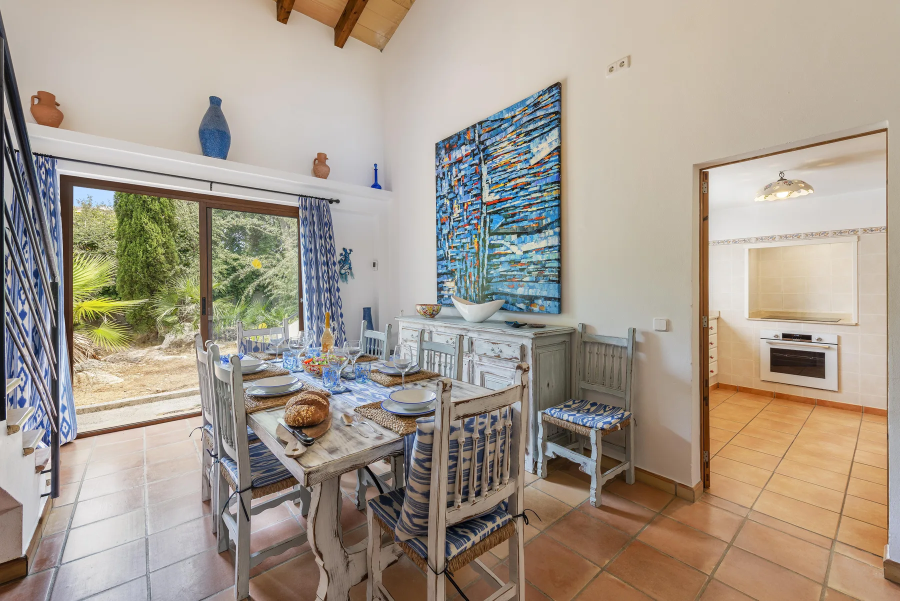 Un comedor con la mesa puesta junto a puertas de vidrio que dan a un jardín.