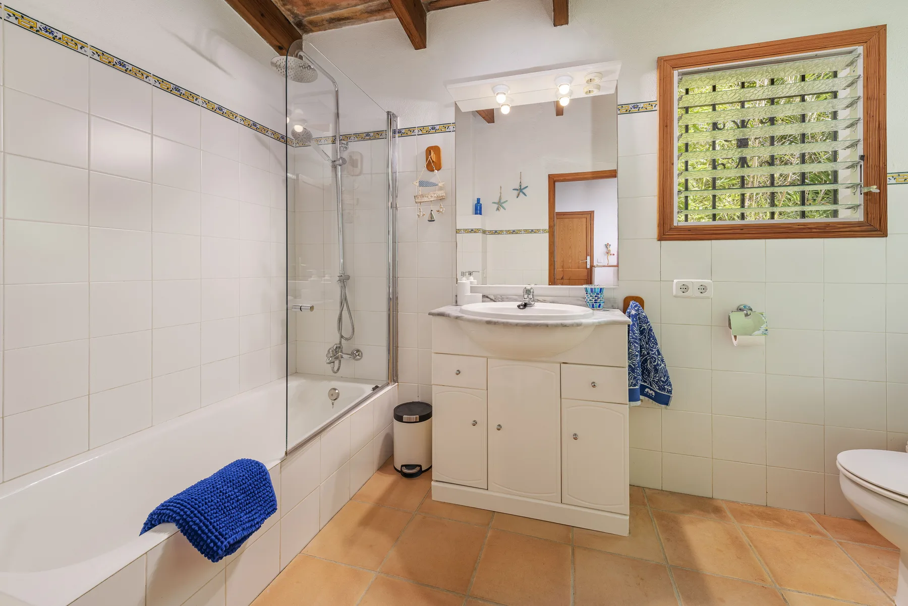 Un baño alicatado con bañera, lavabo y ventana.