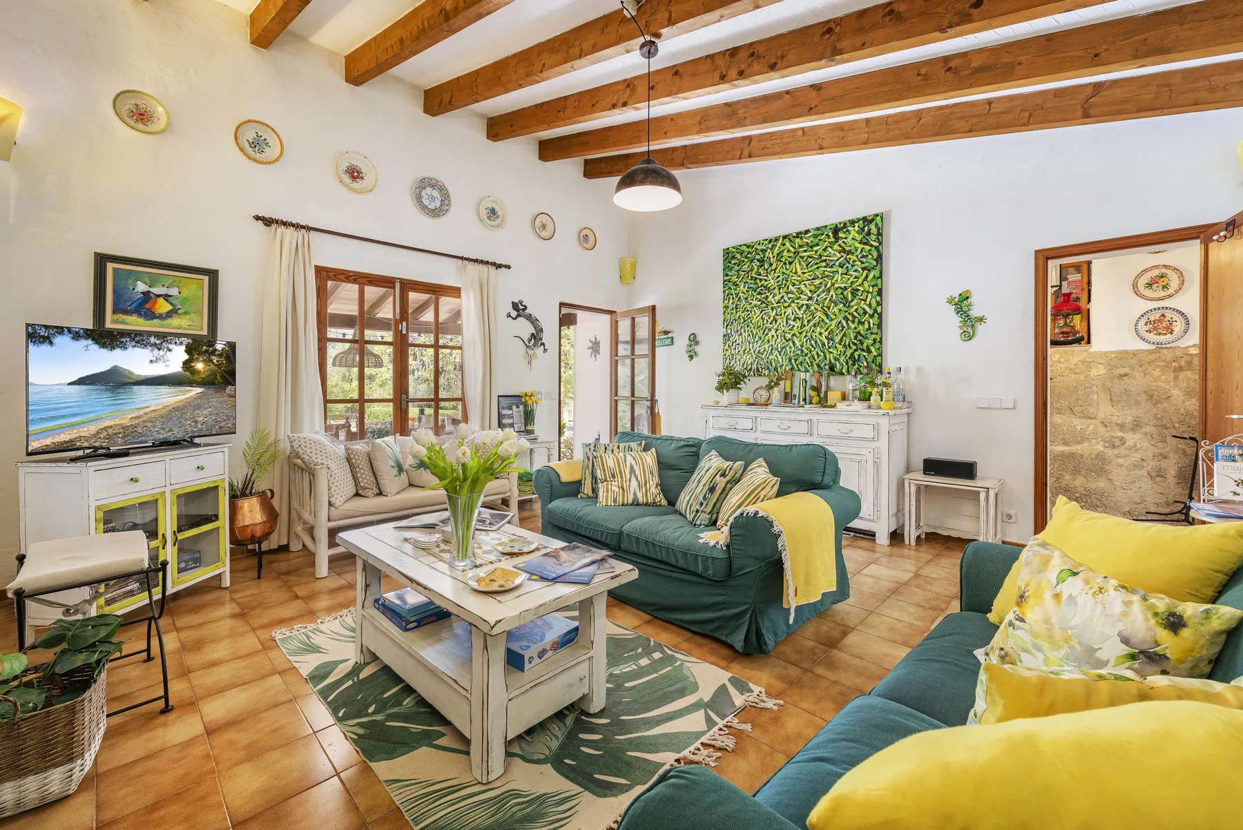Una sala luminosa con asientos verdes, una mesa de centro y vigas de madera expuestas.