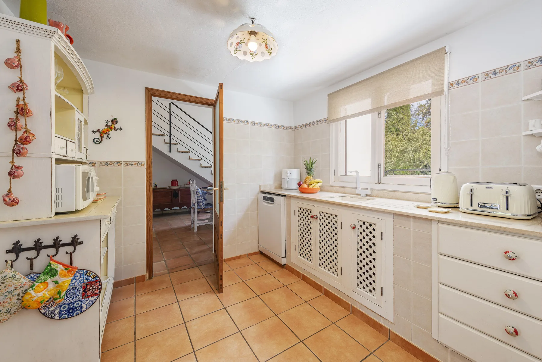 Una cocina luminosa con paredes alicatadas y una ventana con vistas a los árboles.