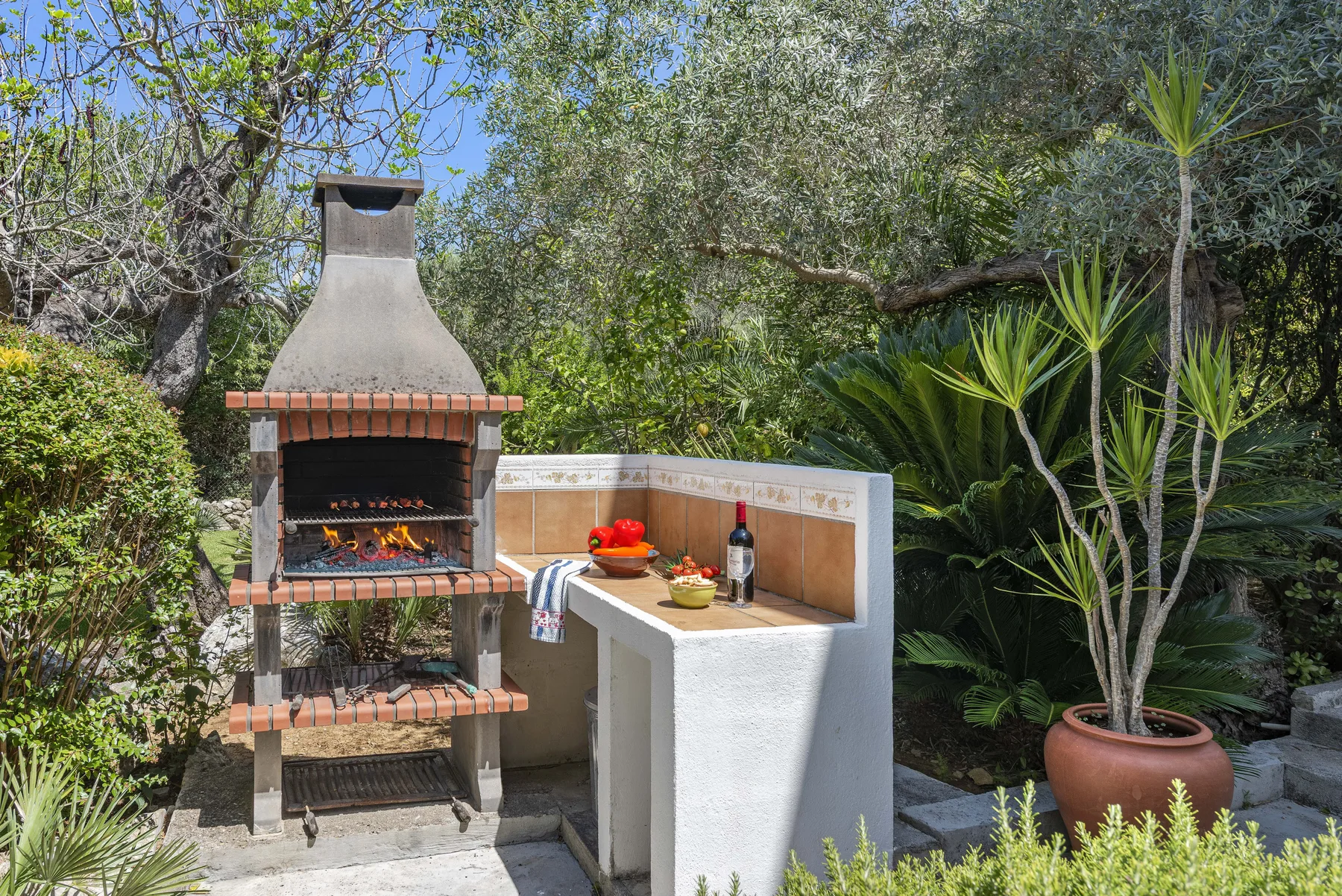 Una zona de barbacoa al aire libre con parrilla y mostrador de azulejos.