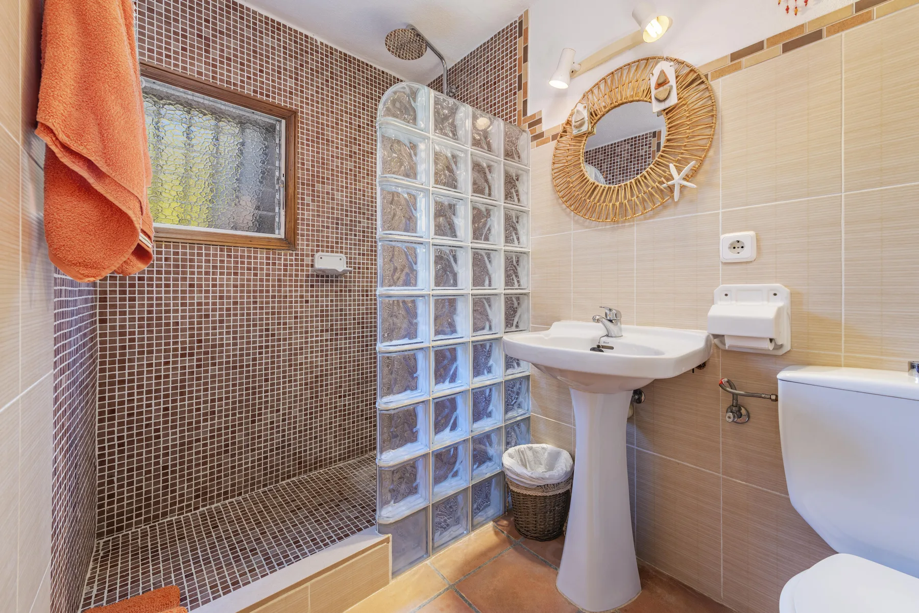 Un baño con lavabo, inodoro y zona de ducha alicatada.