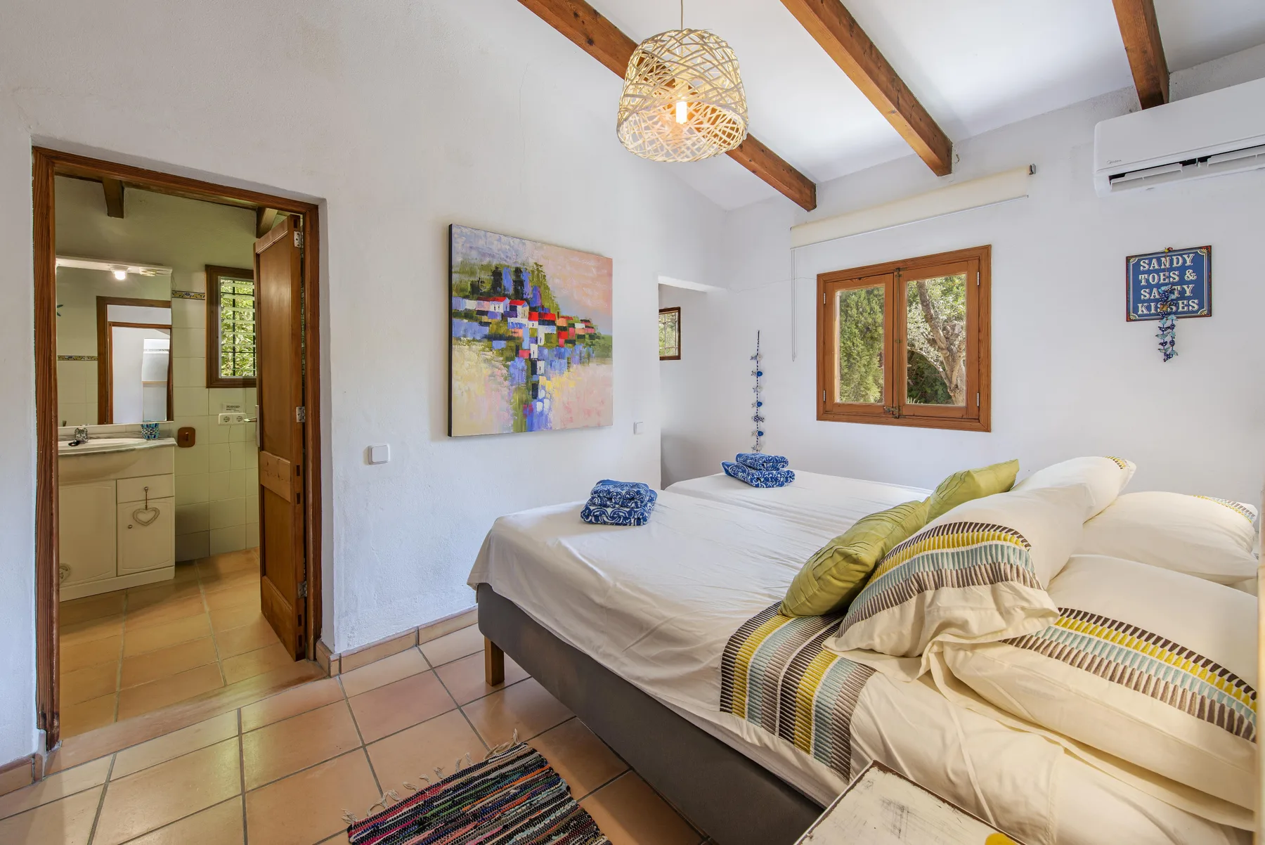 Un dormitorio con una cama grande, una ventana y una puerta abierta a un baño.