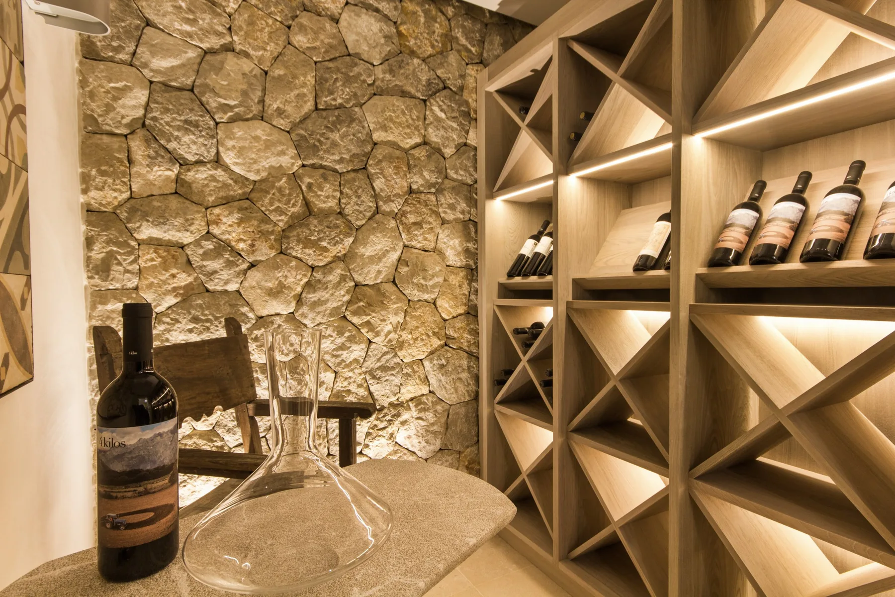 A wine display with bottles in wooden racks beside a stone wall.