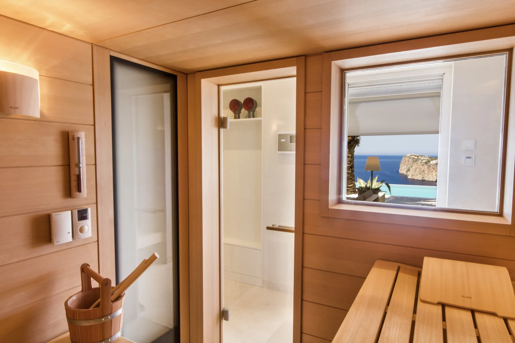 A wood-paneled room with an open doorway and a window overlooking the sea.