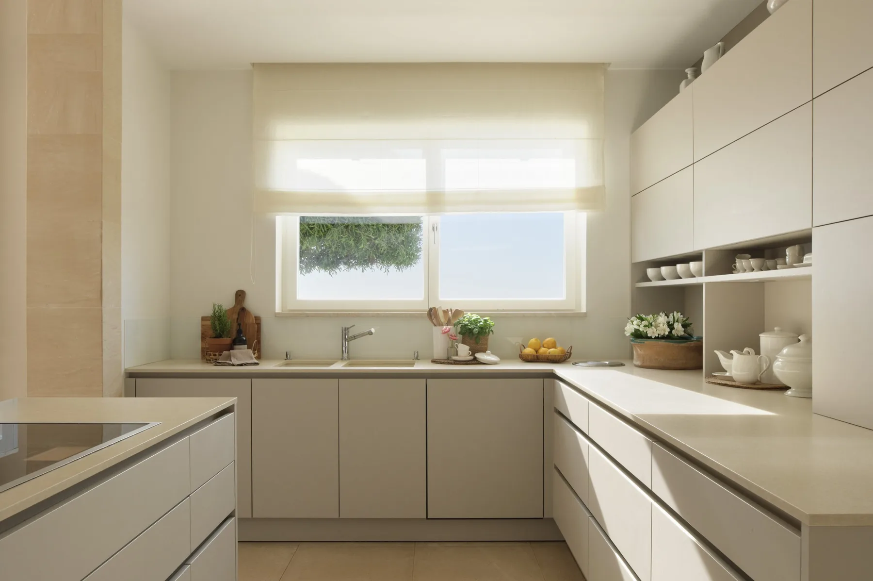 A bright kitchen with pale cabinetry, broad countertops, and a window above the sink.