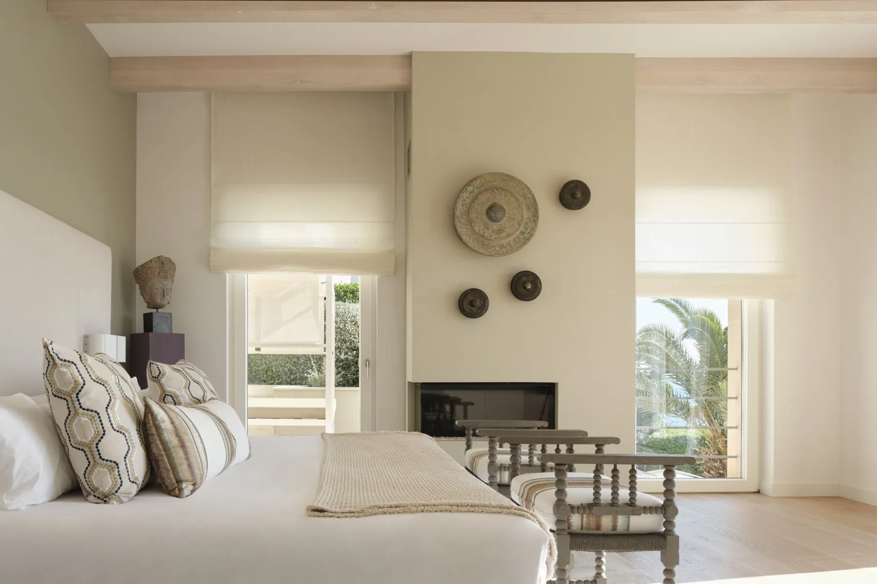 A bright bedroom with a bed, decorative wall plates, and a view through the windows.