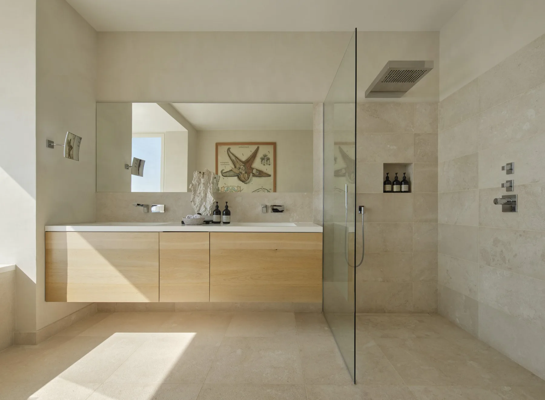 A bright bathroom with a long vanity and a glass shower screen.