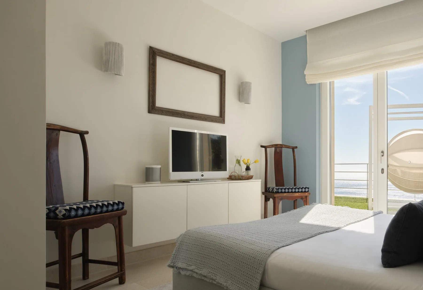 A bright bedroom with a bed, television, and sliding glass doors.