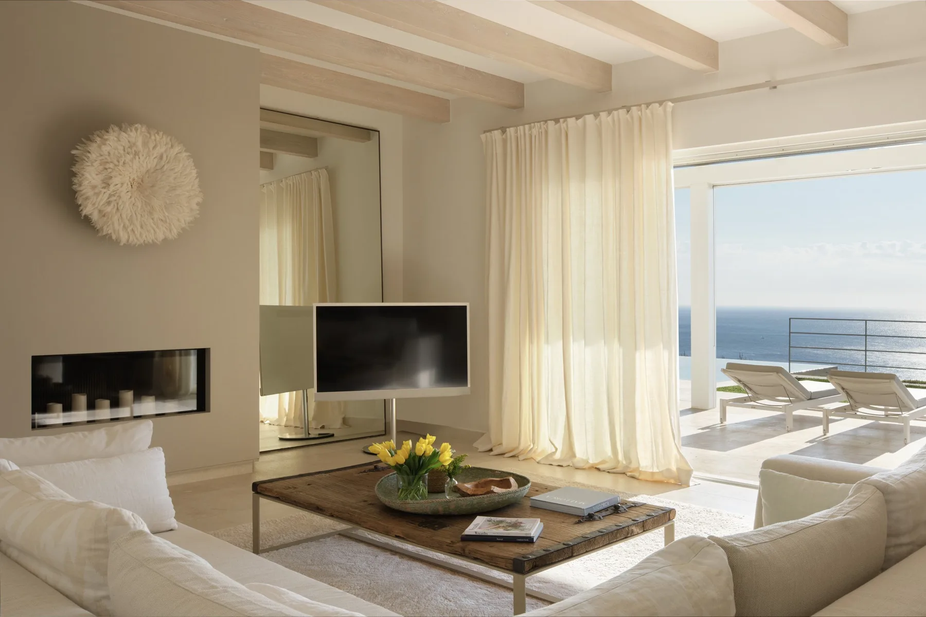 A bright living room opens onto a sea view, with seating and a television.