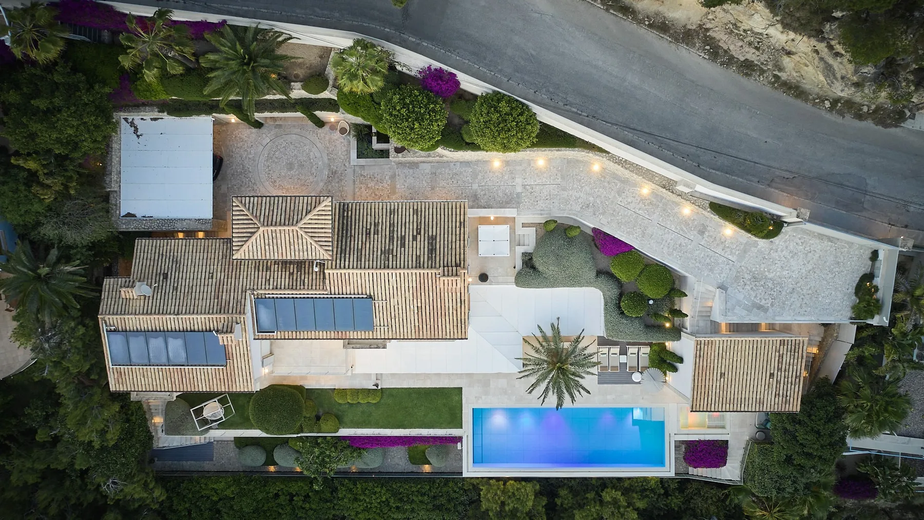 An aerial view shows a landscaped property with a long building and a bright blue pool.