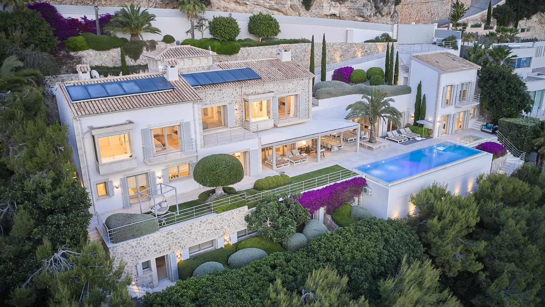 A modern villa with a swimming pool, terraces, and landscaped gardens.