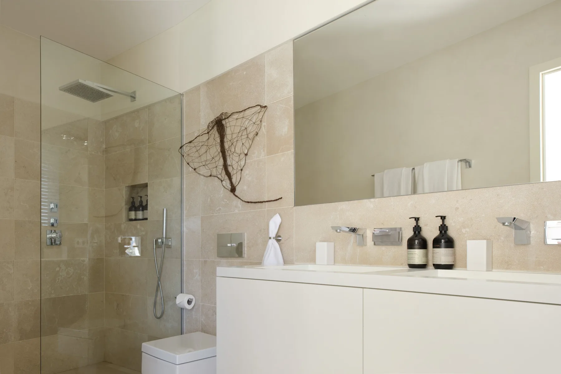 A bright bathroom with a glass shower and a wide vanity.