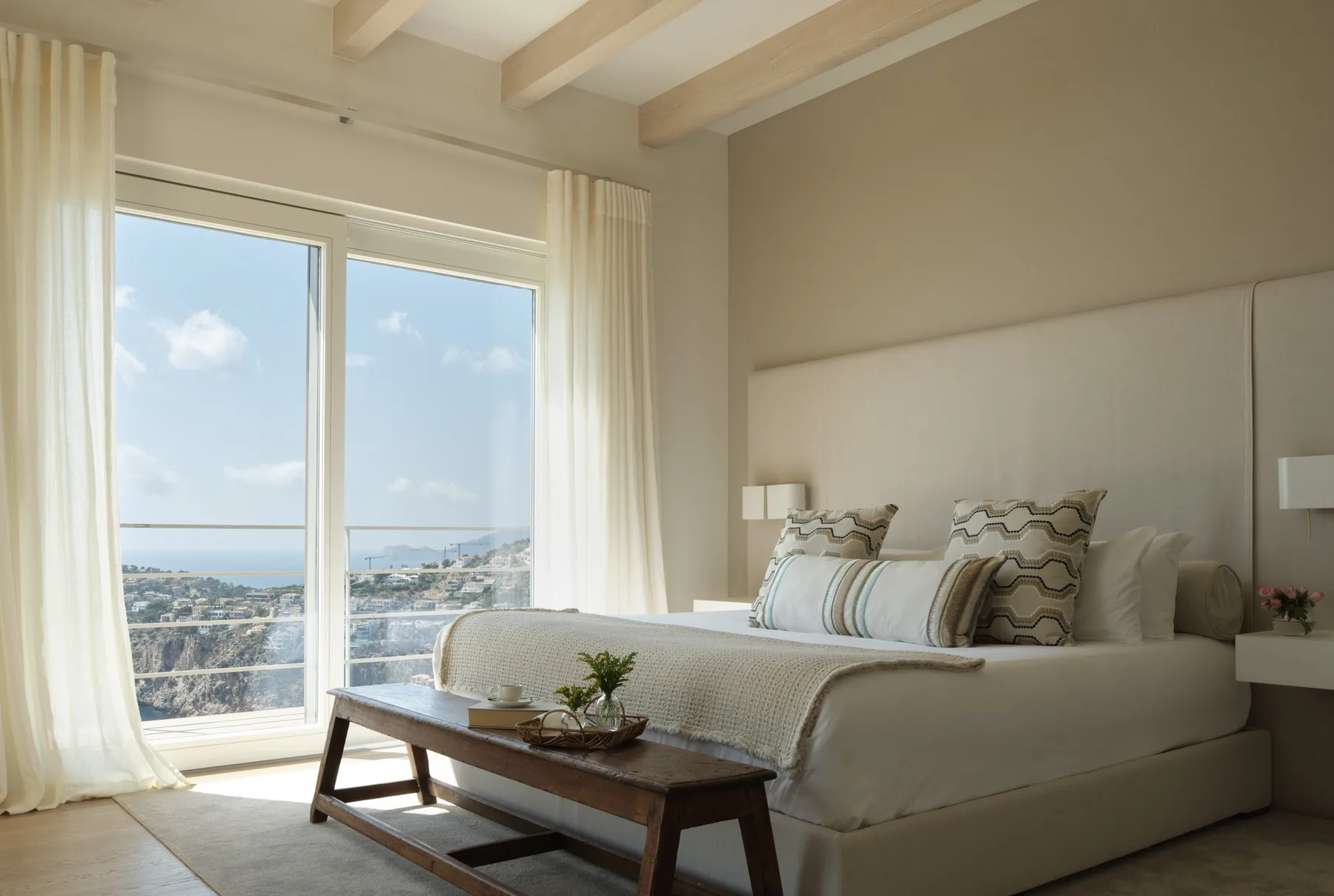 A bright bedroom with a large bed beside tall windows.