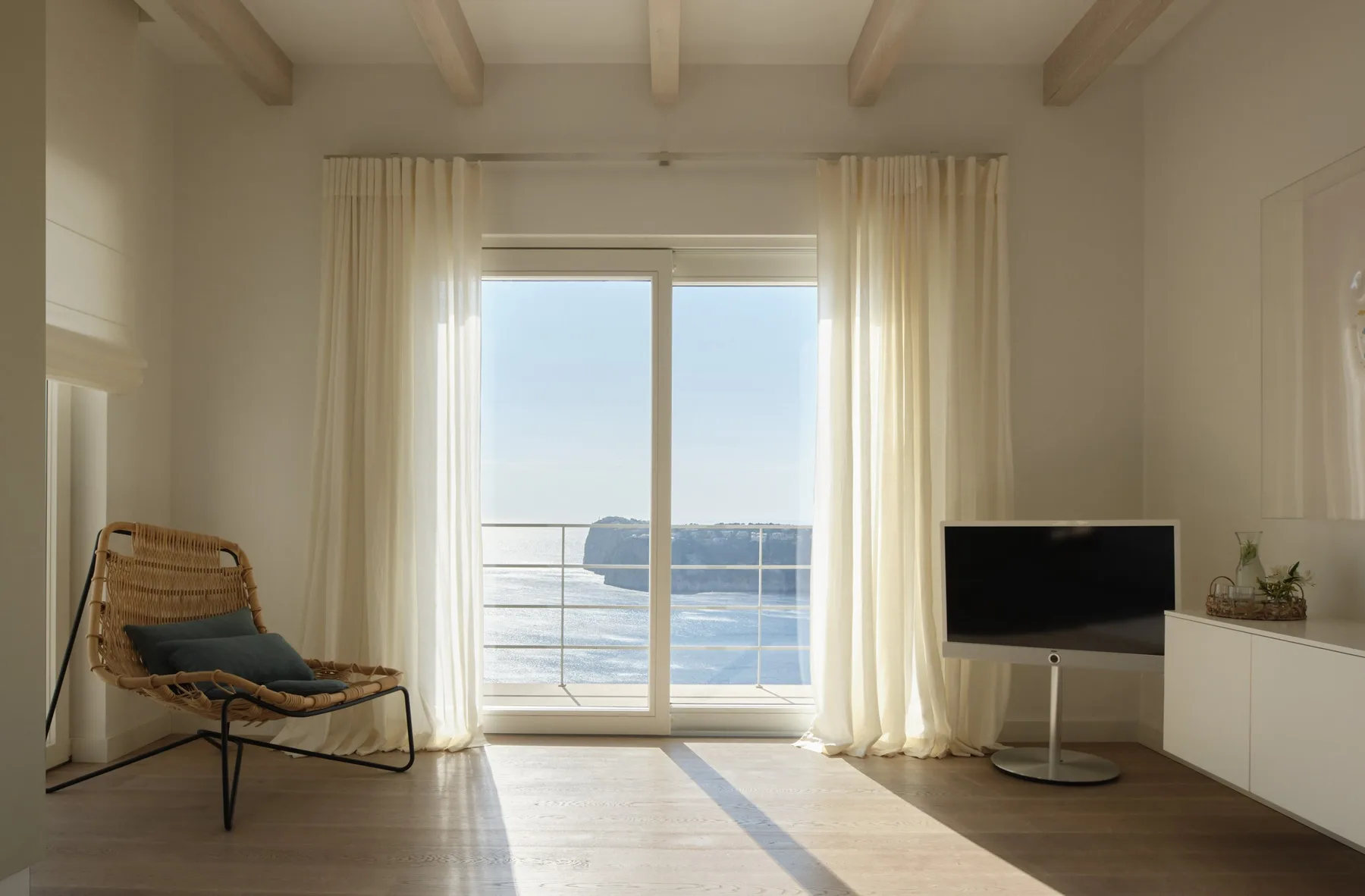 A bright living room opens onto a balcony overlooking the water.