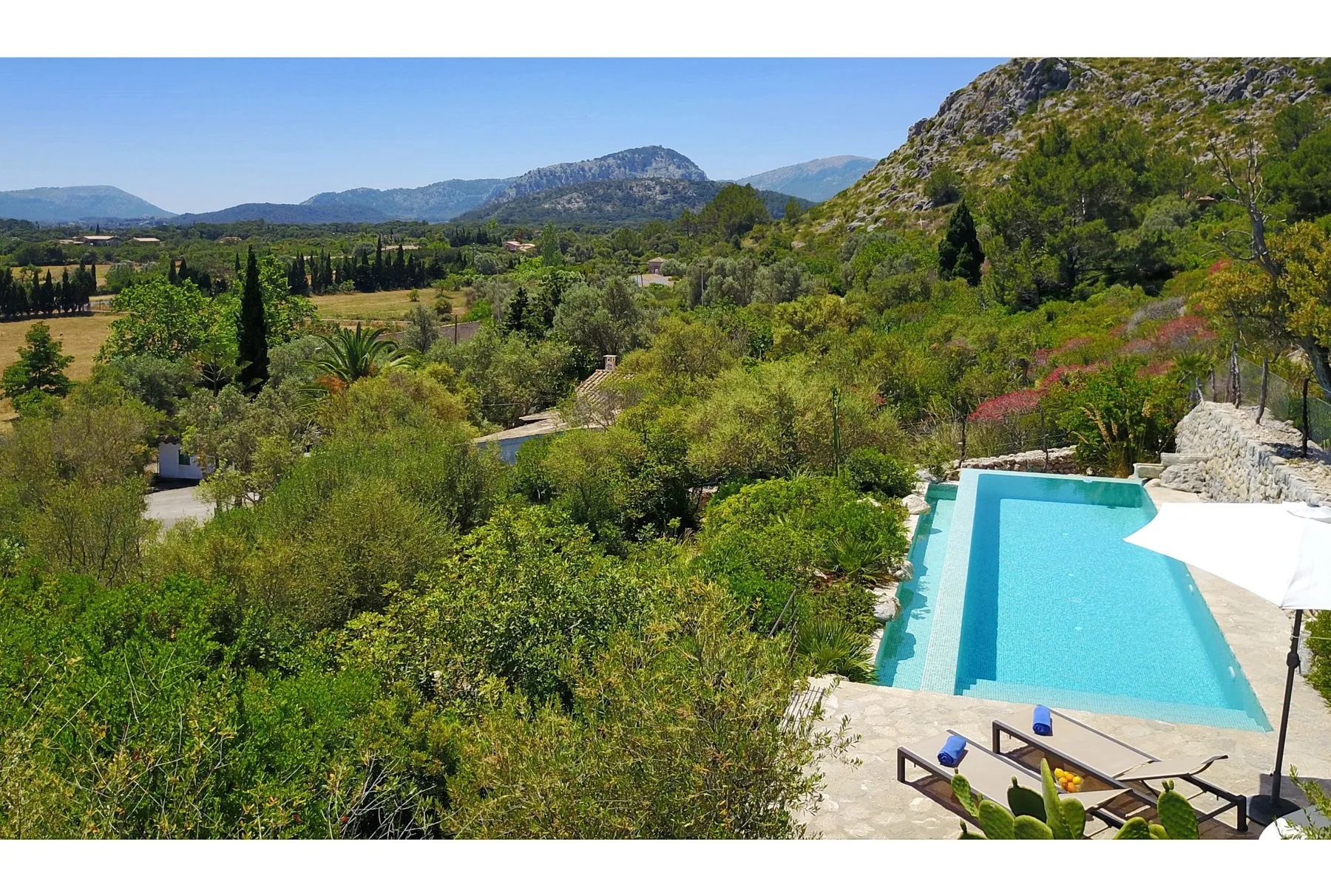 Una piscina exterior da a un valle verde y montañas lejanas.