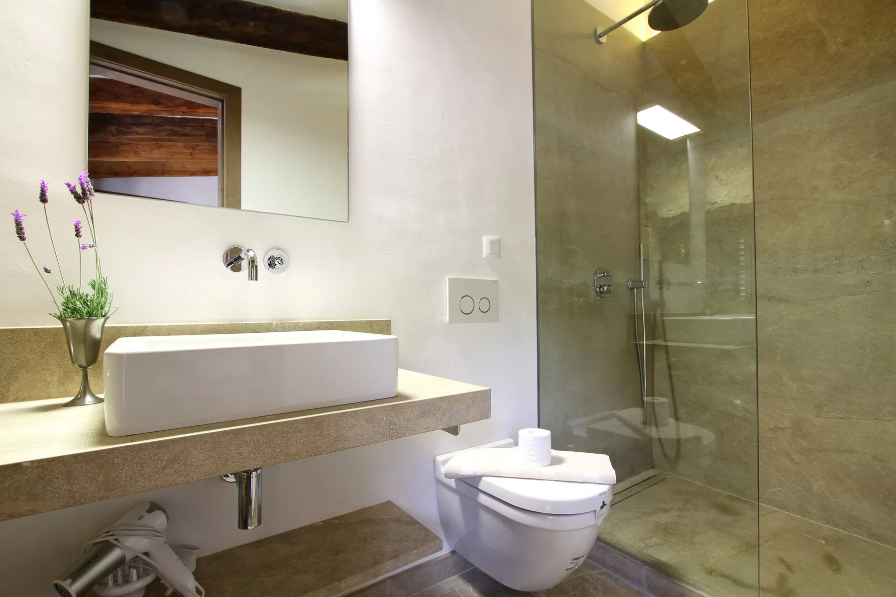 Un baño moderno con lavabo sobre encimera y ducha con mampara de vidrio.