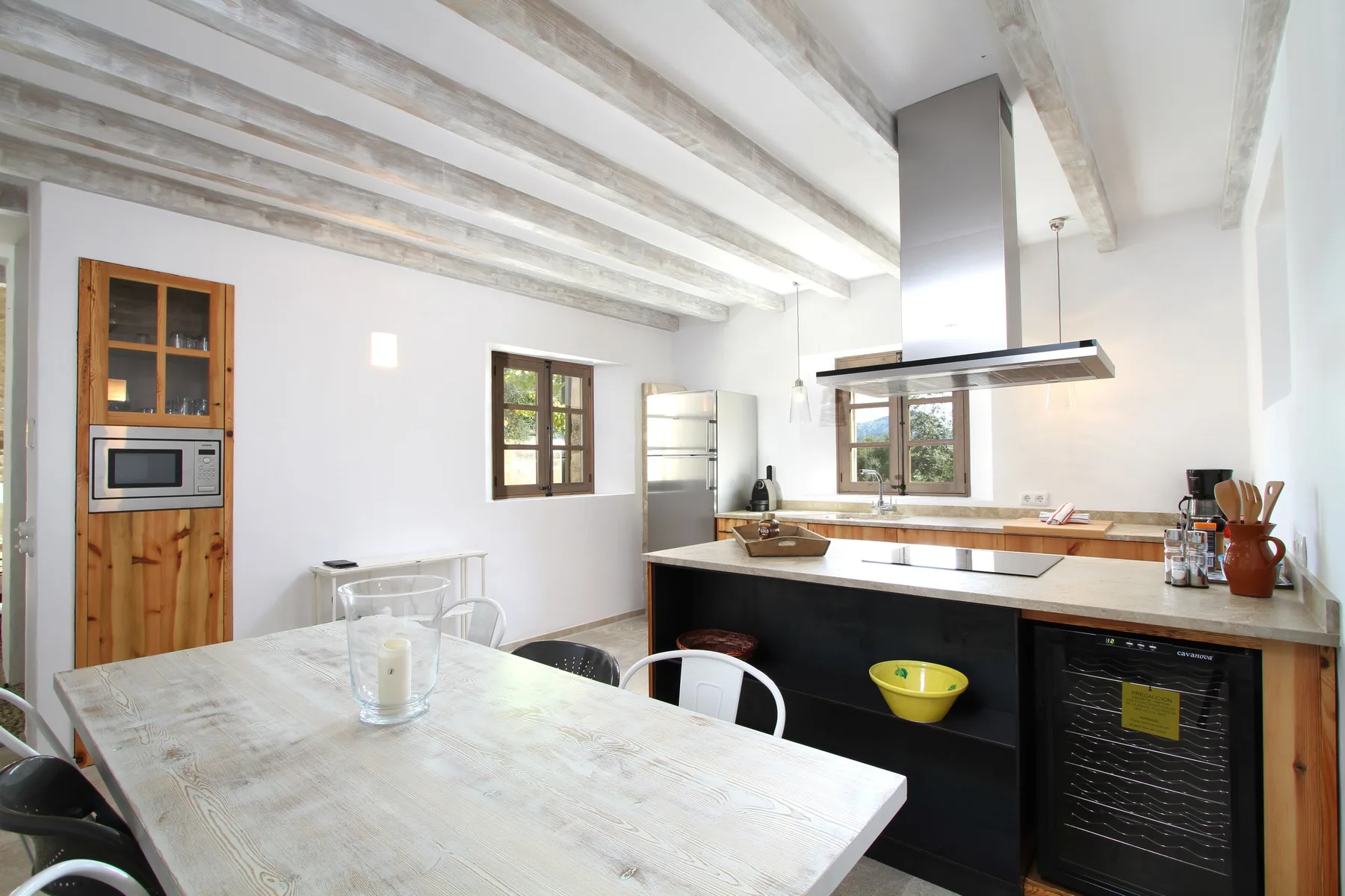 Una cocina luminosa con una isla amplia y una mesa de comedor de madera.