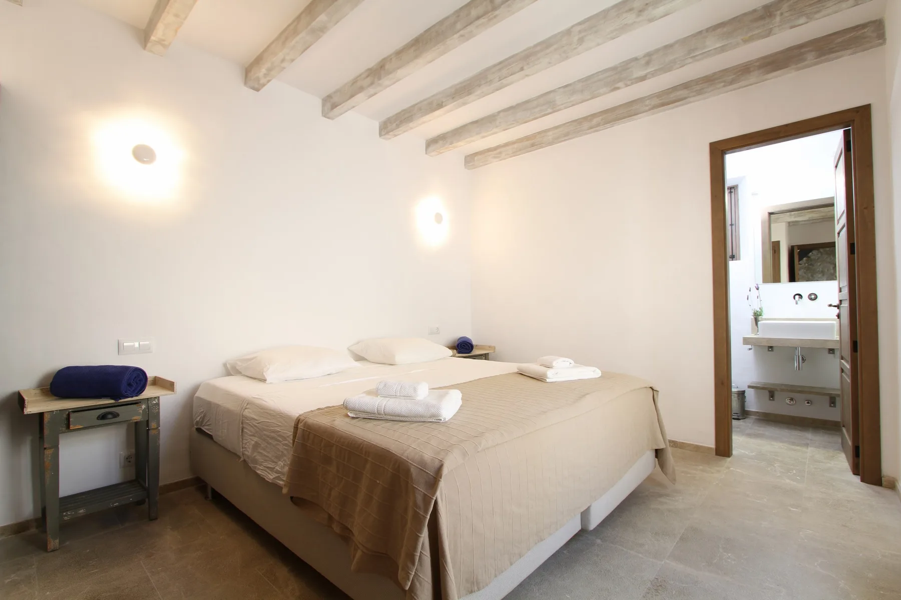 Un dormitorio con una cama grande y vigas expuestas en el techo.