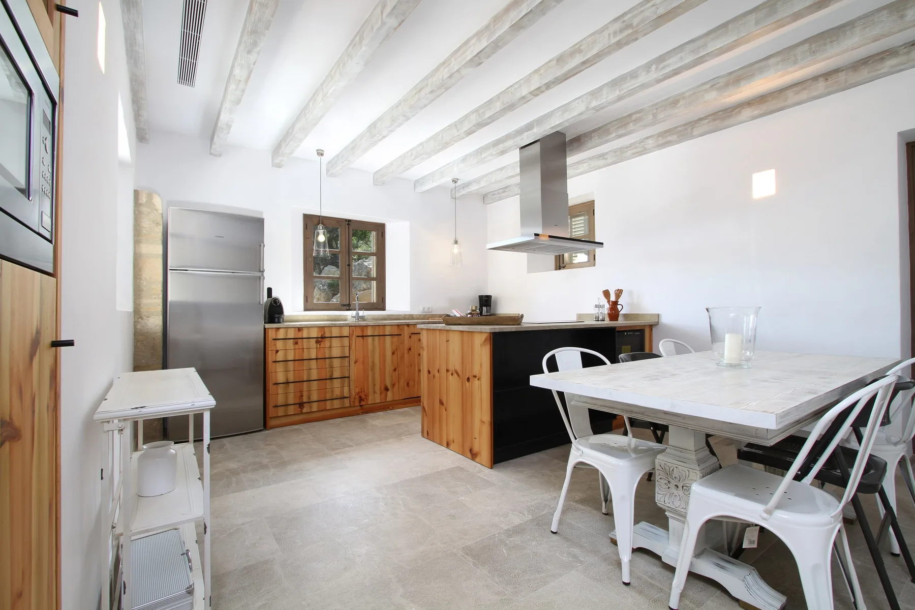 Una cocina luminosa con gabinetes de madera y una mesa grande.