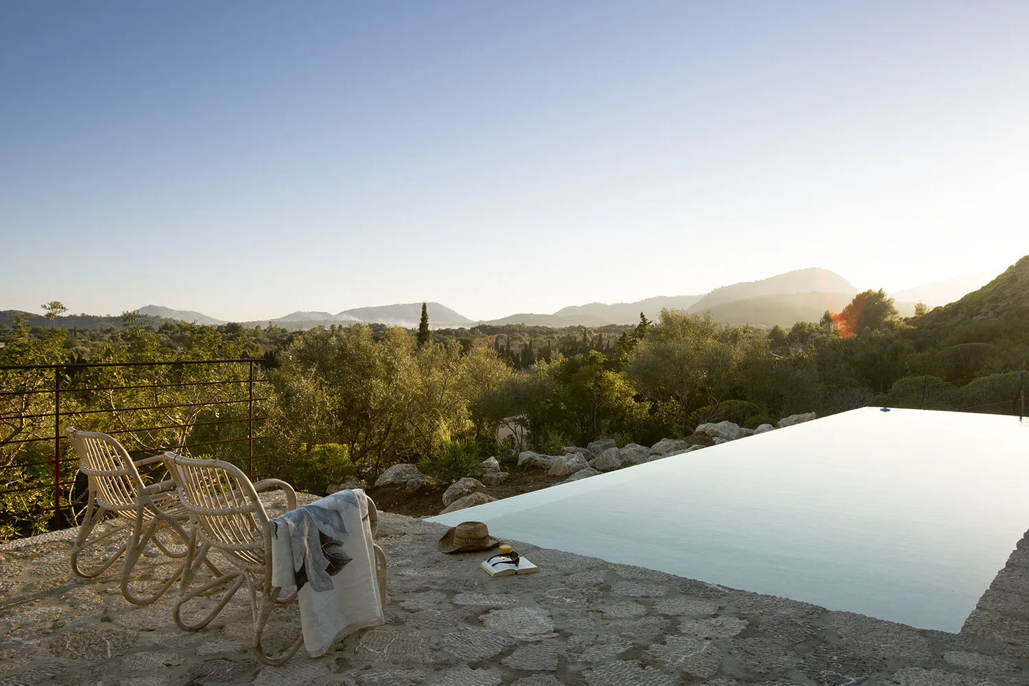 Una piscina infinita al aire libre ofrece vistas a un paisaje arbolado y colinas lejanas.