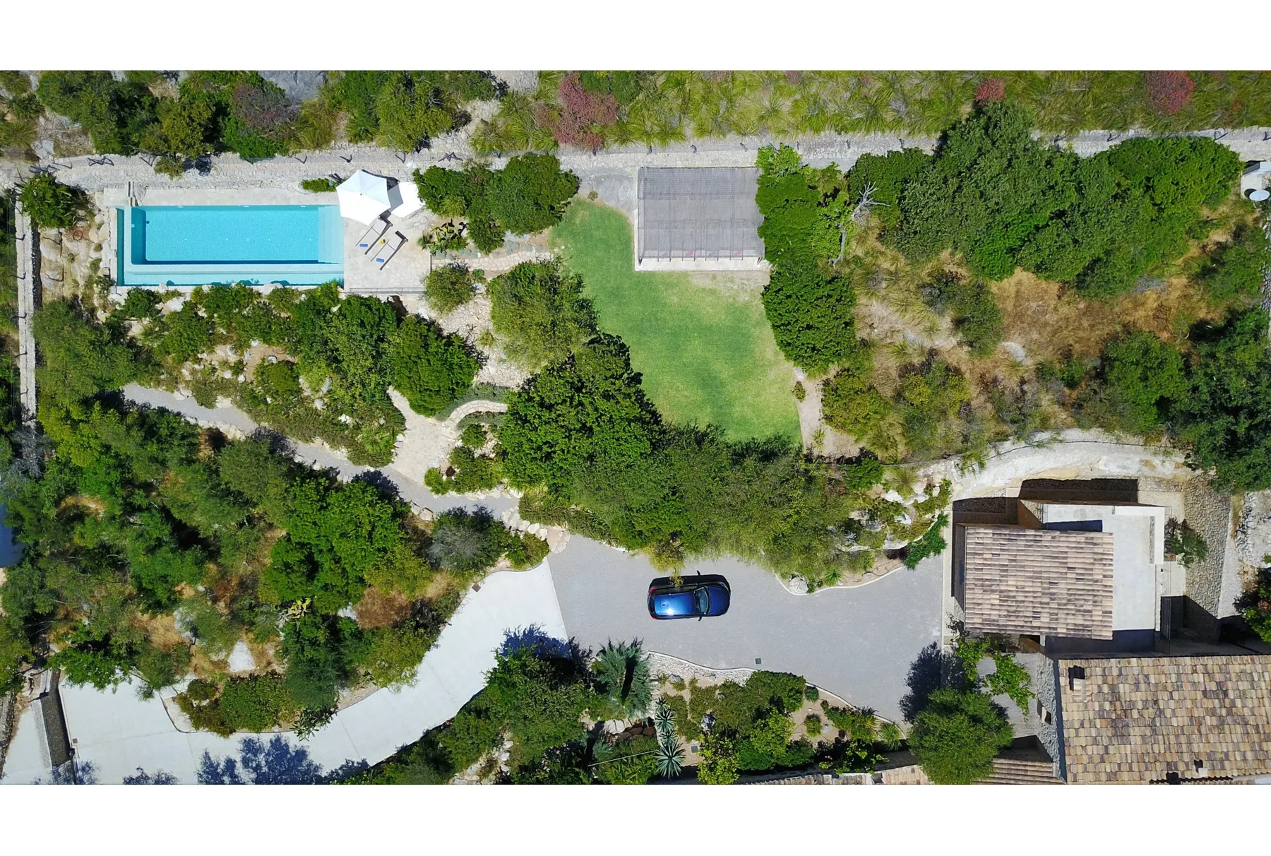 Vista aérea de una propiedad ajardinada con piscina y caminos pavimentados.