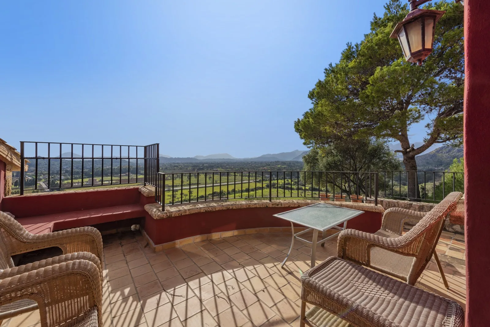 A tiled terrace with outdoor seating overlooks a green valley.