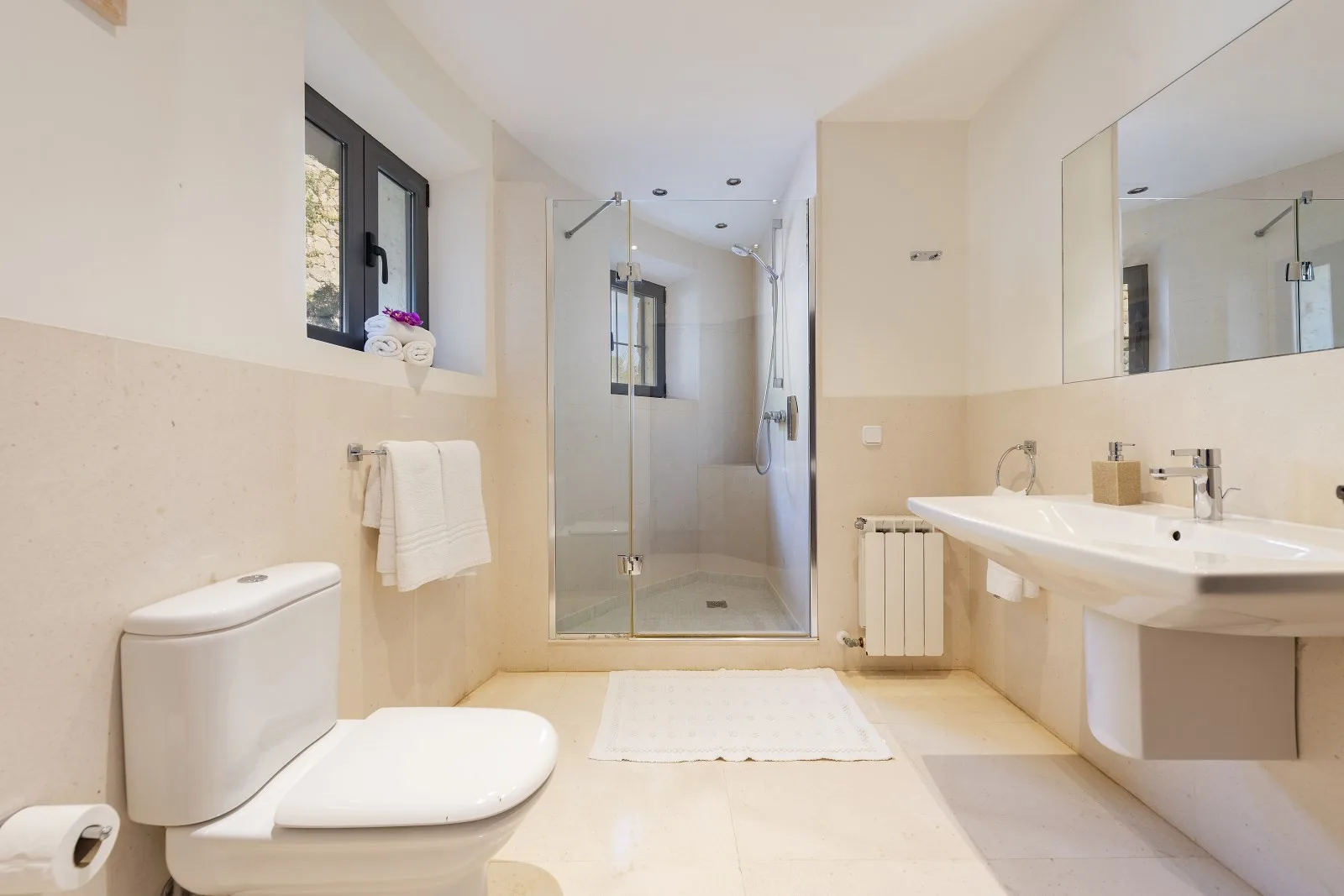 A bright bathroom with a glass shower, bathtub, and sink.