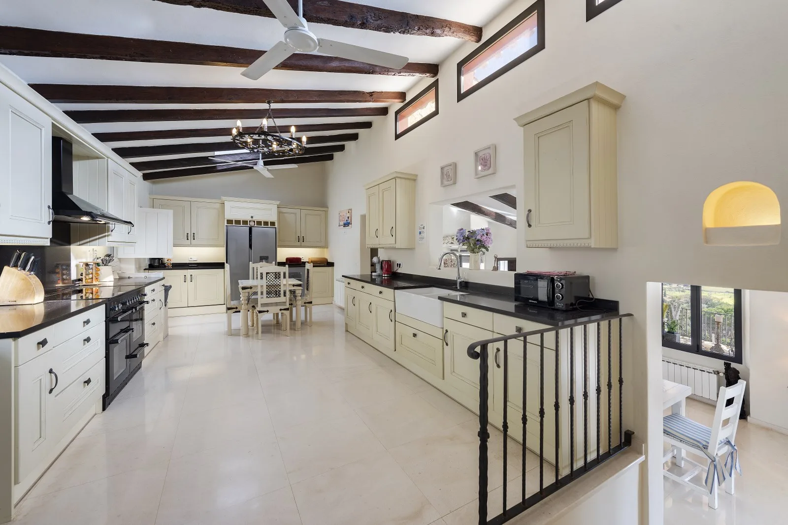 A spacious kitchen with pale cabinetry, dark countertops, and a dining table.