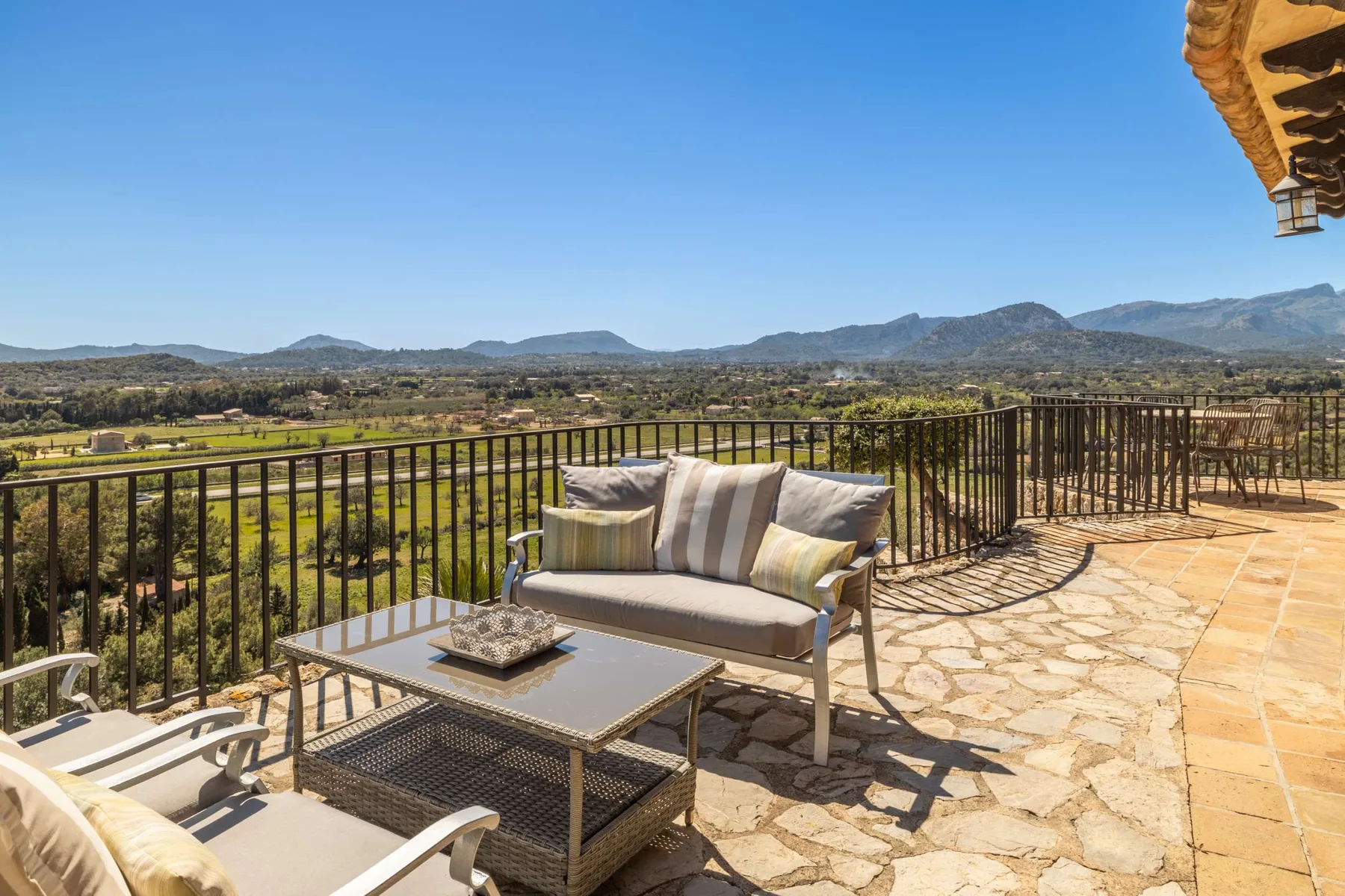 A terrace seating area overlooks fields and distant mountains.
