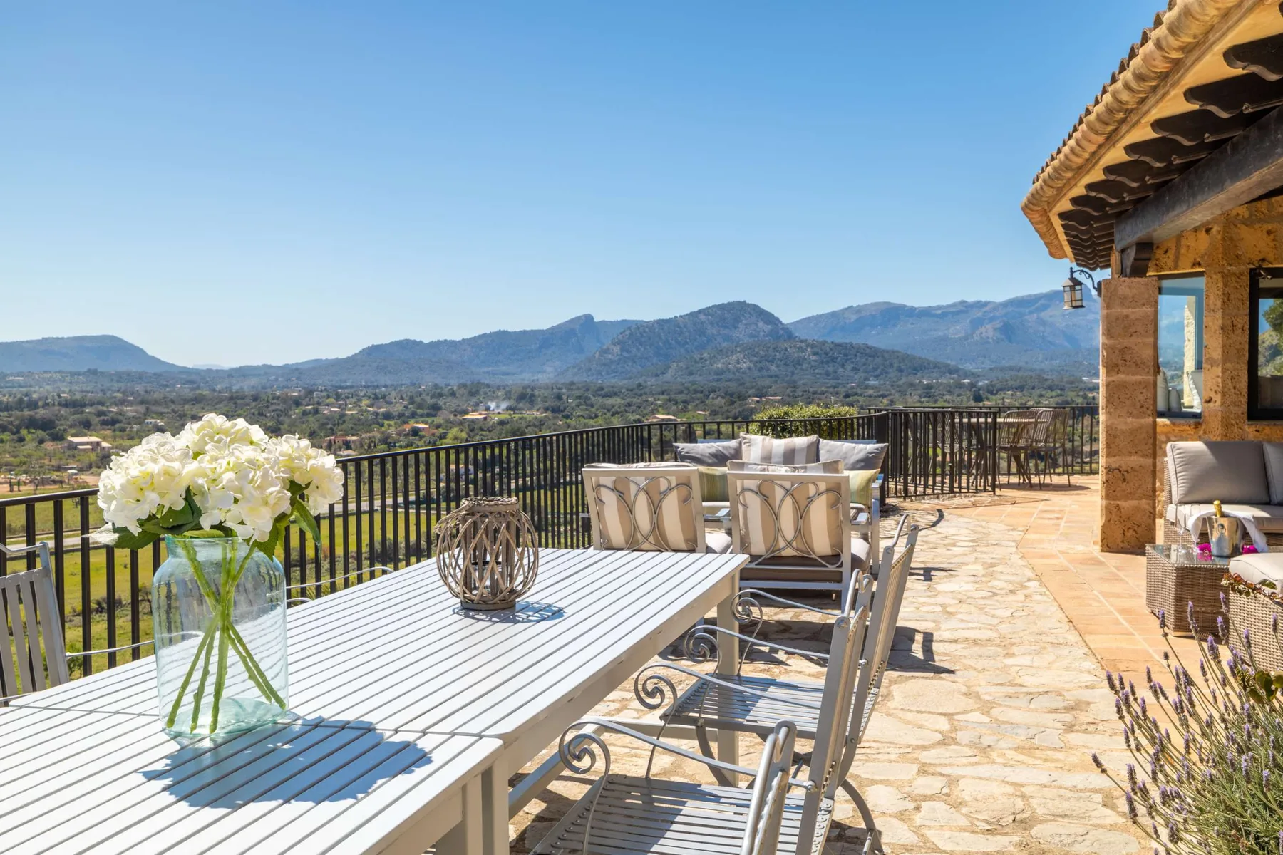 An outdoor dining terrace overlooks a valley and mountain range.
